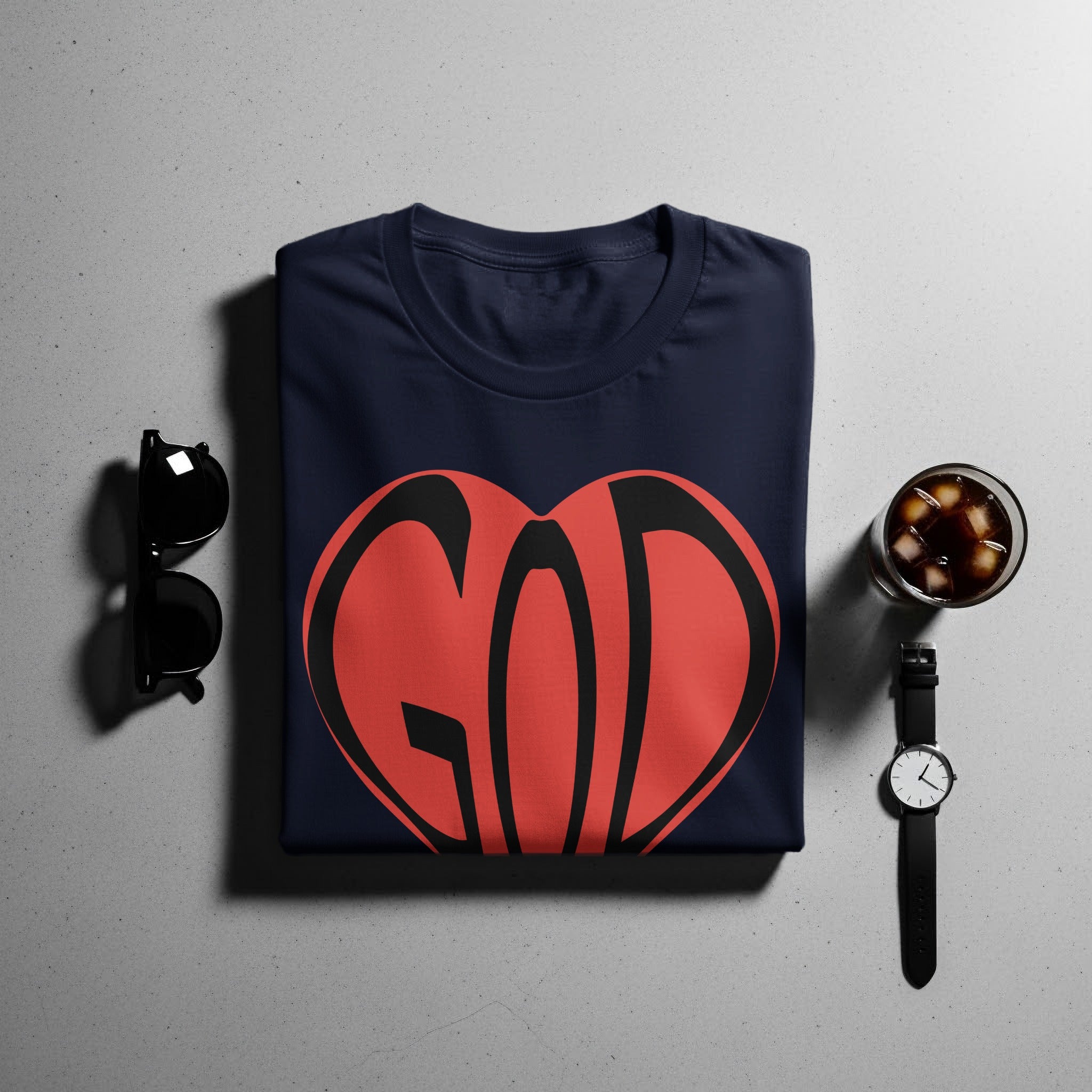 Navy t-shirt with red and black "GOD" heart graphic, sunglasses, drink, and watch.