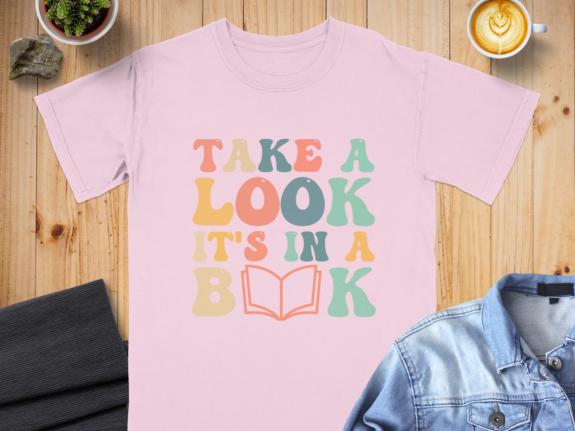 Pink t-shirt with "Take a look it's in a book" in retro font.
