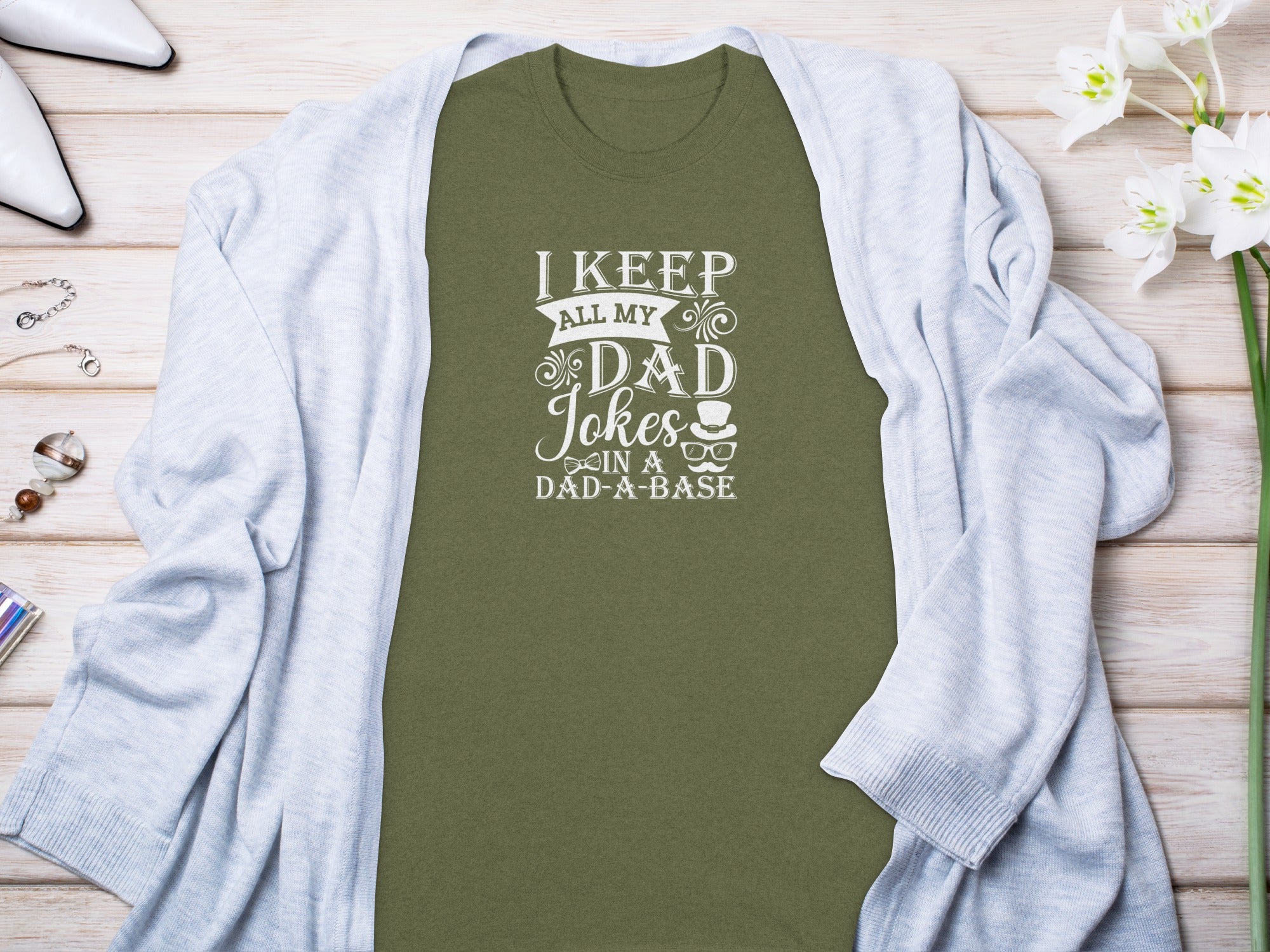Green t-shirt with white text reading "I KEEP ALL MY DAD Jokes IN A DAD-A-BASE".