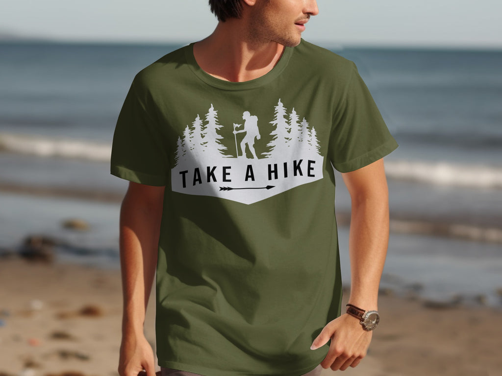 Olive green t-shirt with white "TAKE A HIKE" text, hiker, and trees graphic.