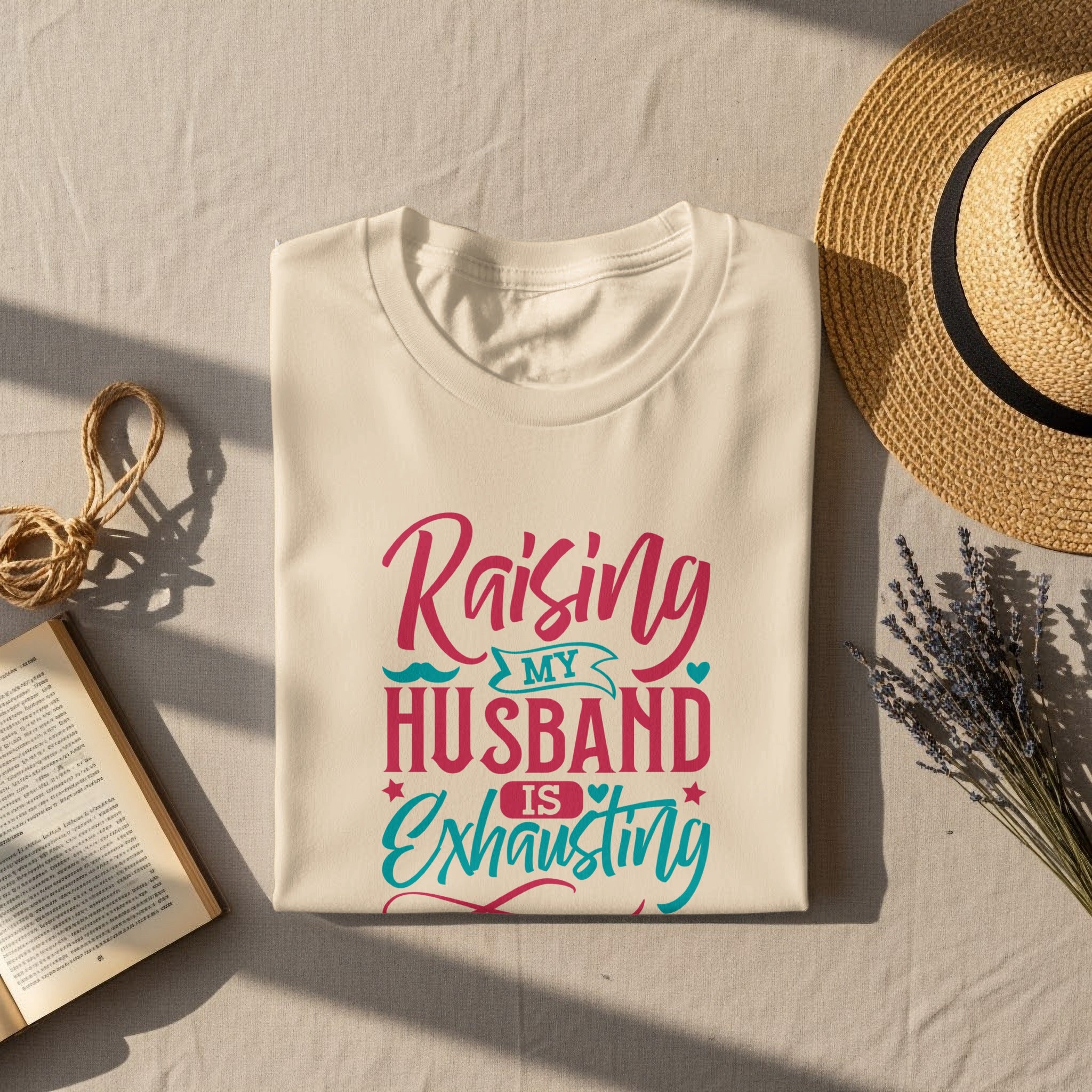 Cream t-shirt with "Raising my husband is exhausting" in pink and teal text.