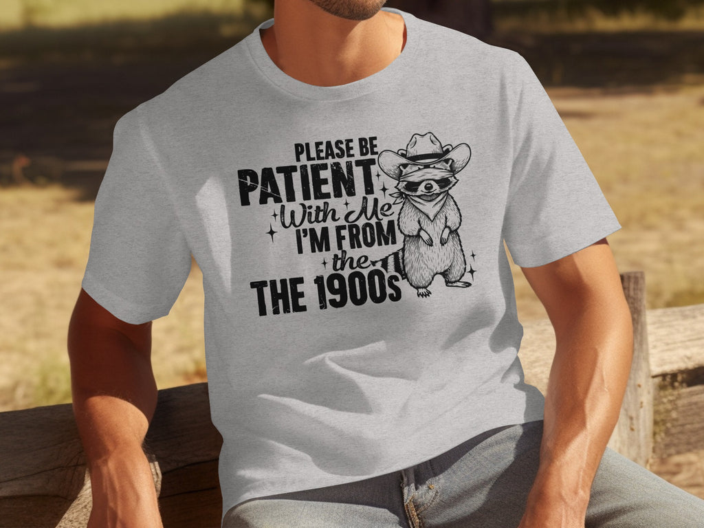 Light grey t-shirt with graphic: "Please Be Patient With Me, I'm From the 1900s" and raccoon.