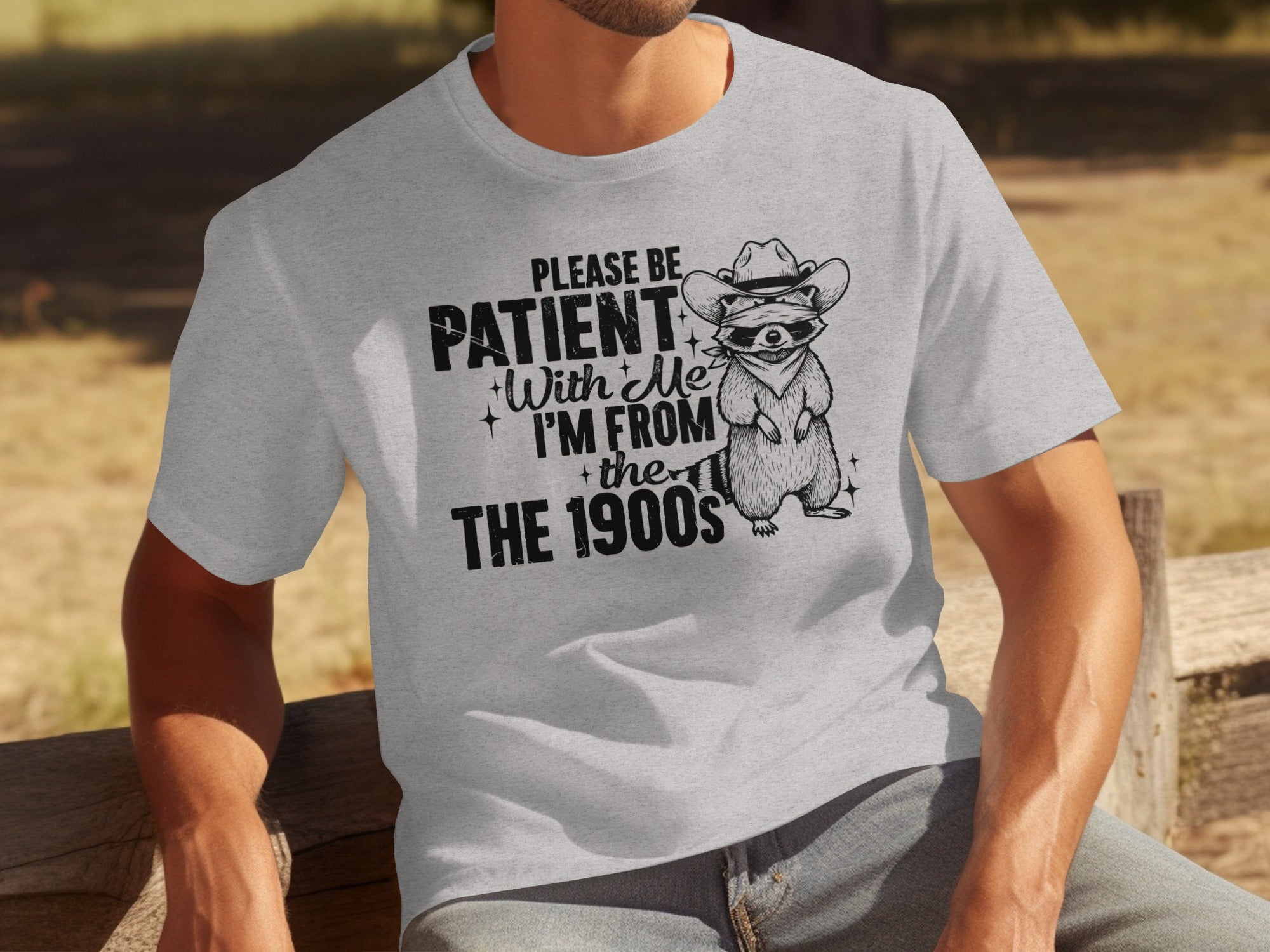 Light grey t-shirt with graphic: "Please Be Patient With Me, I'm From the 1900s" and raccoon.