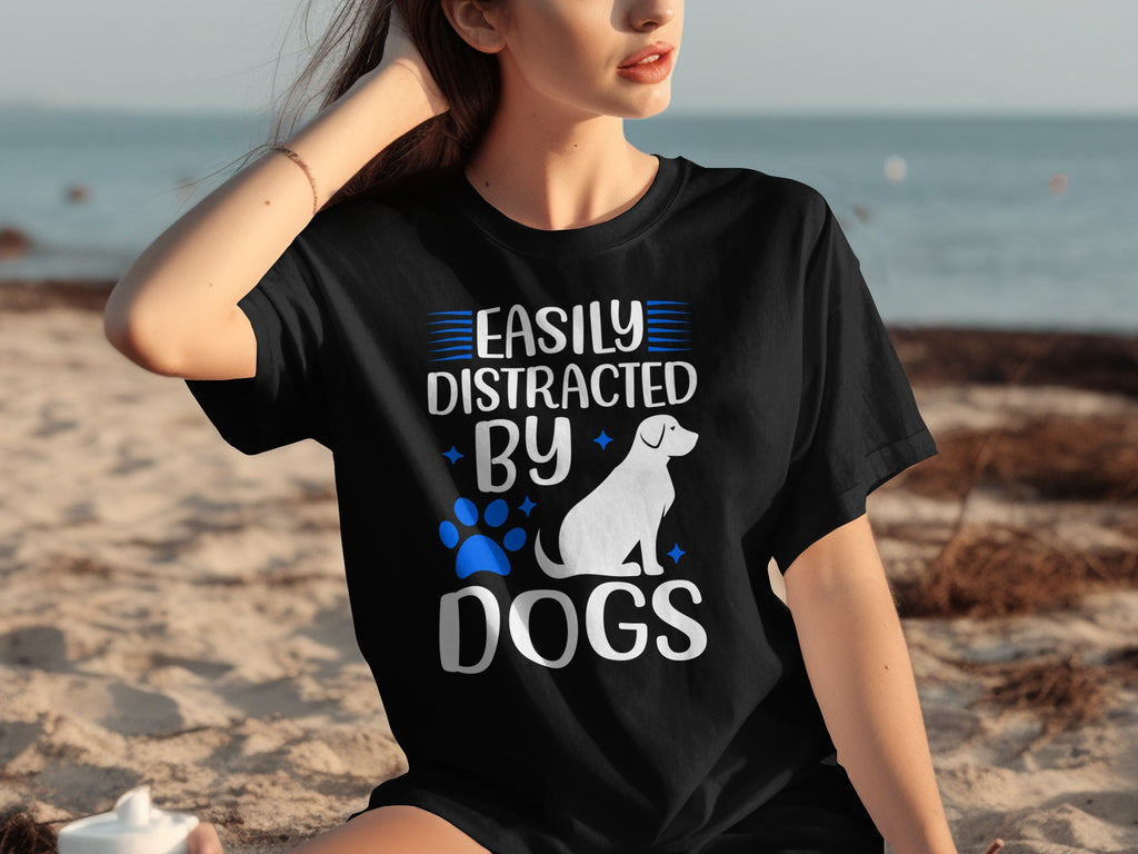 Black t-shirt with "Easily Distracted By Dogs" text and dog graphic on beach.