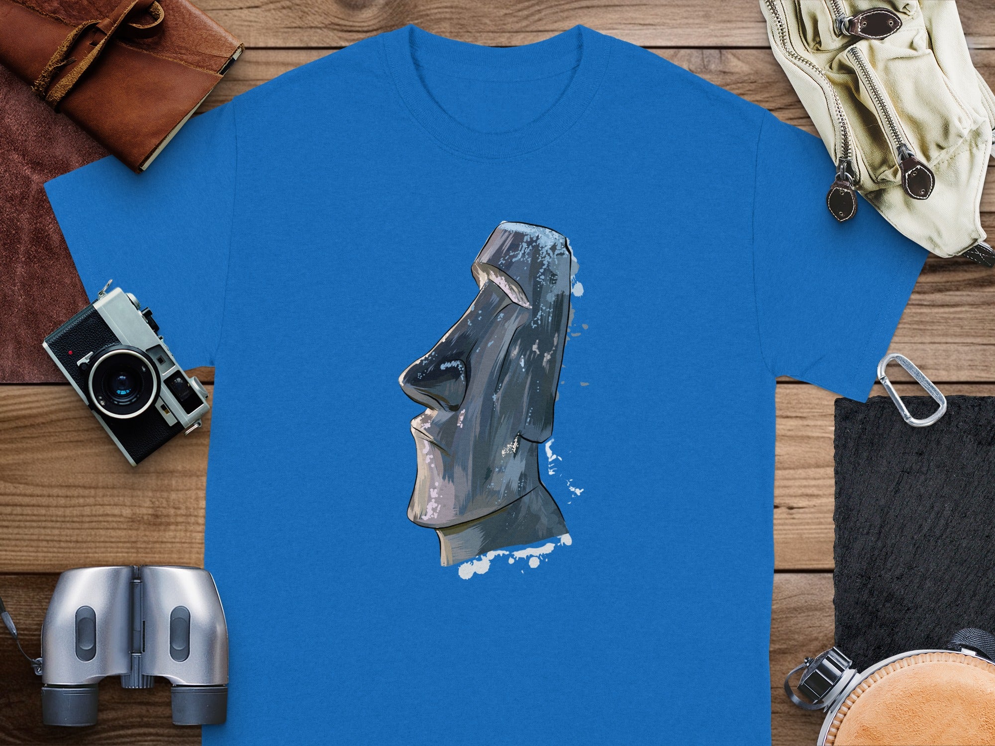 Blue t-shirt with illustration of a Moai statue head and splatters.