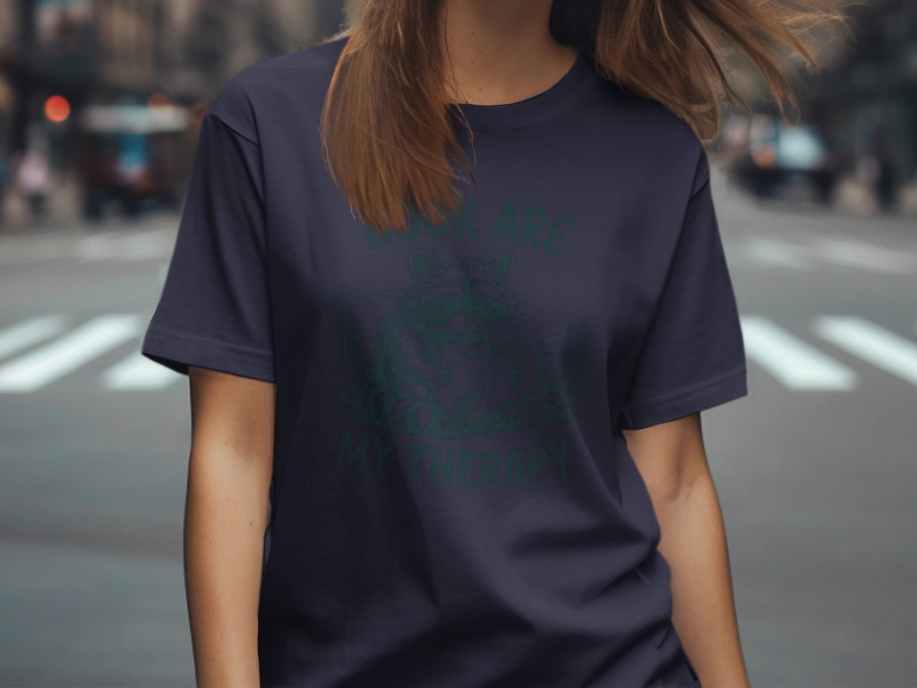 Dark t-shirt with green raccoon reading "Books Are My Therapy" graphic.
