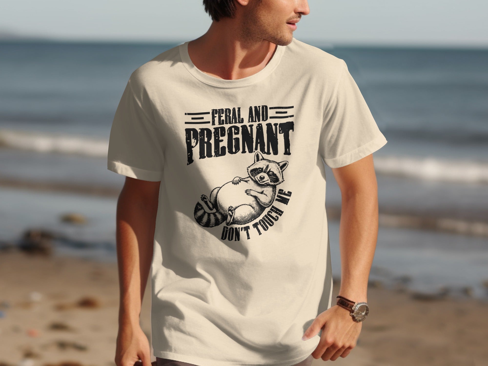 Cream t-shirt with raccoon graphic and text "Feral and Pregnant Don't Touch Me".