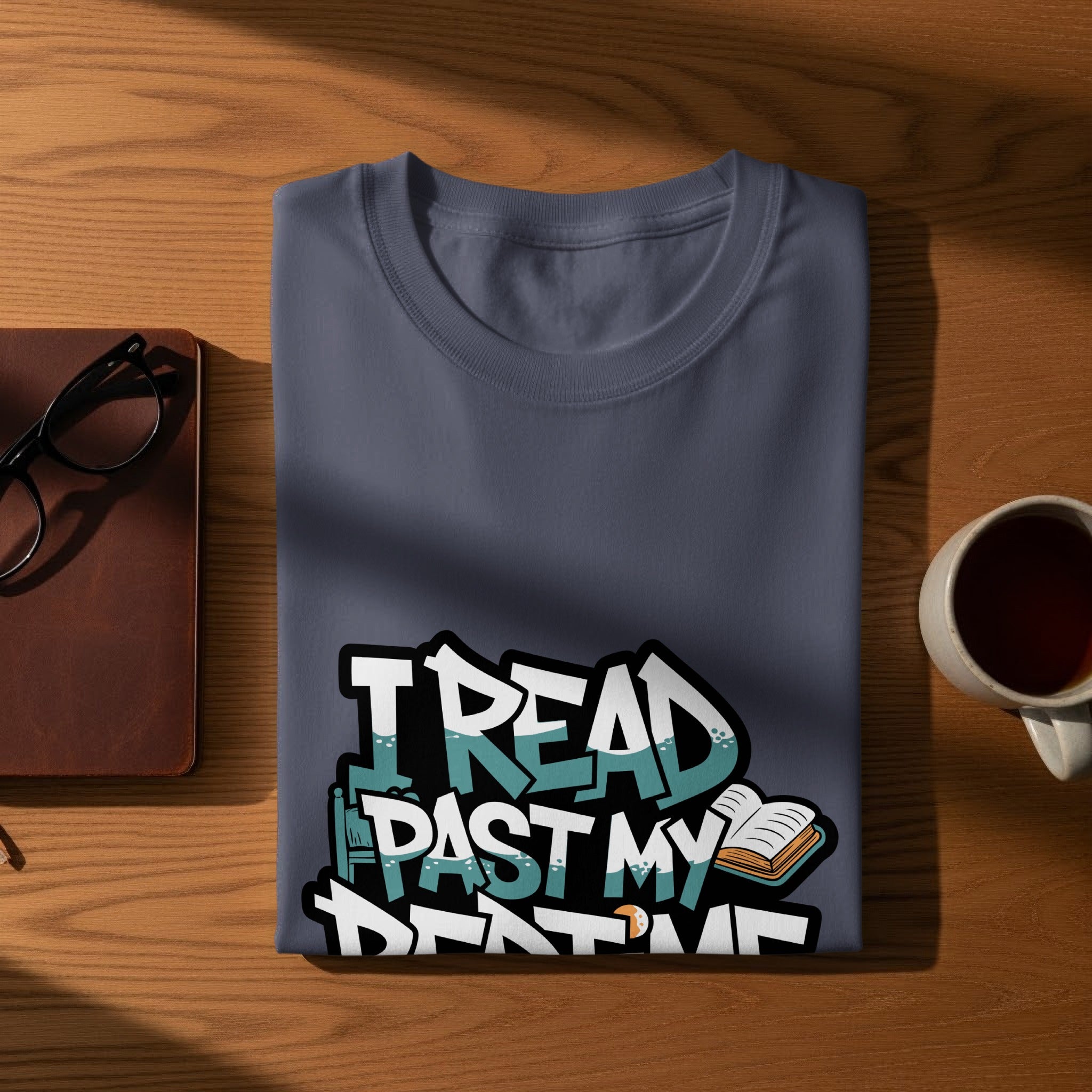 Folded t-shirt with "I read past my bedtime" graphic, book, and glasses.