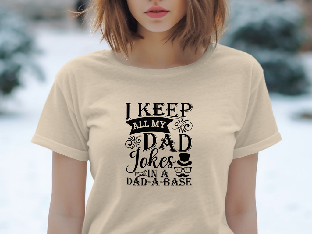 Cream t-shirt with "I KEEP ALL MY DAD JOKES IN A DAD-A-BASE" text and graphics.