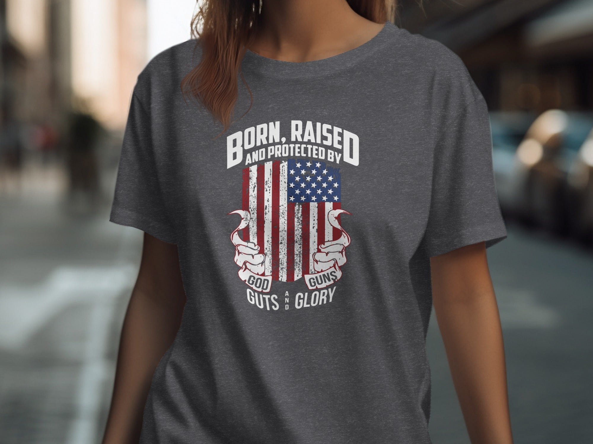 Dark gray t-shirt with American flag graphic and text "Born, Raised and Protected by God, Guns, Guts and Glory".