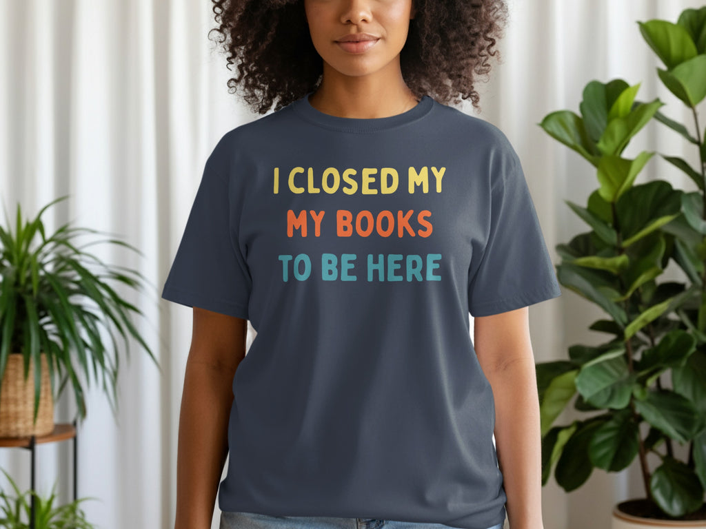 Dark t-shirt with yellow, orange, and teal text reading "I CLOSED MY BOOKS TO BE HERE".
