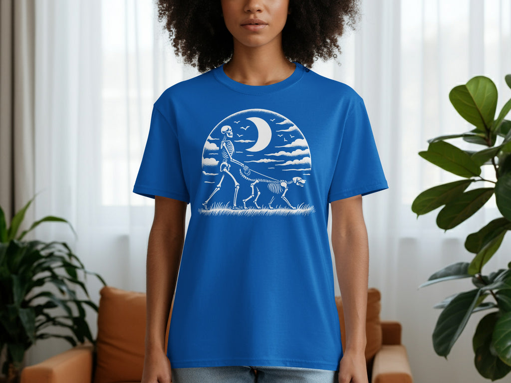 Blue t-shirt with white skeleton walking dog under crescent moon and clouds.