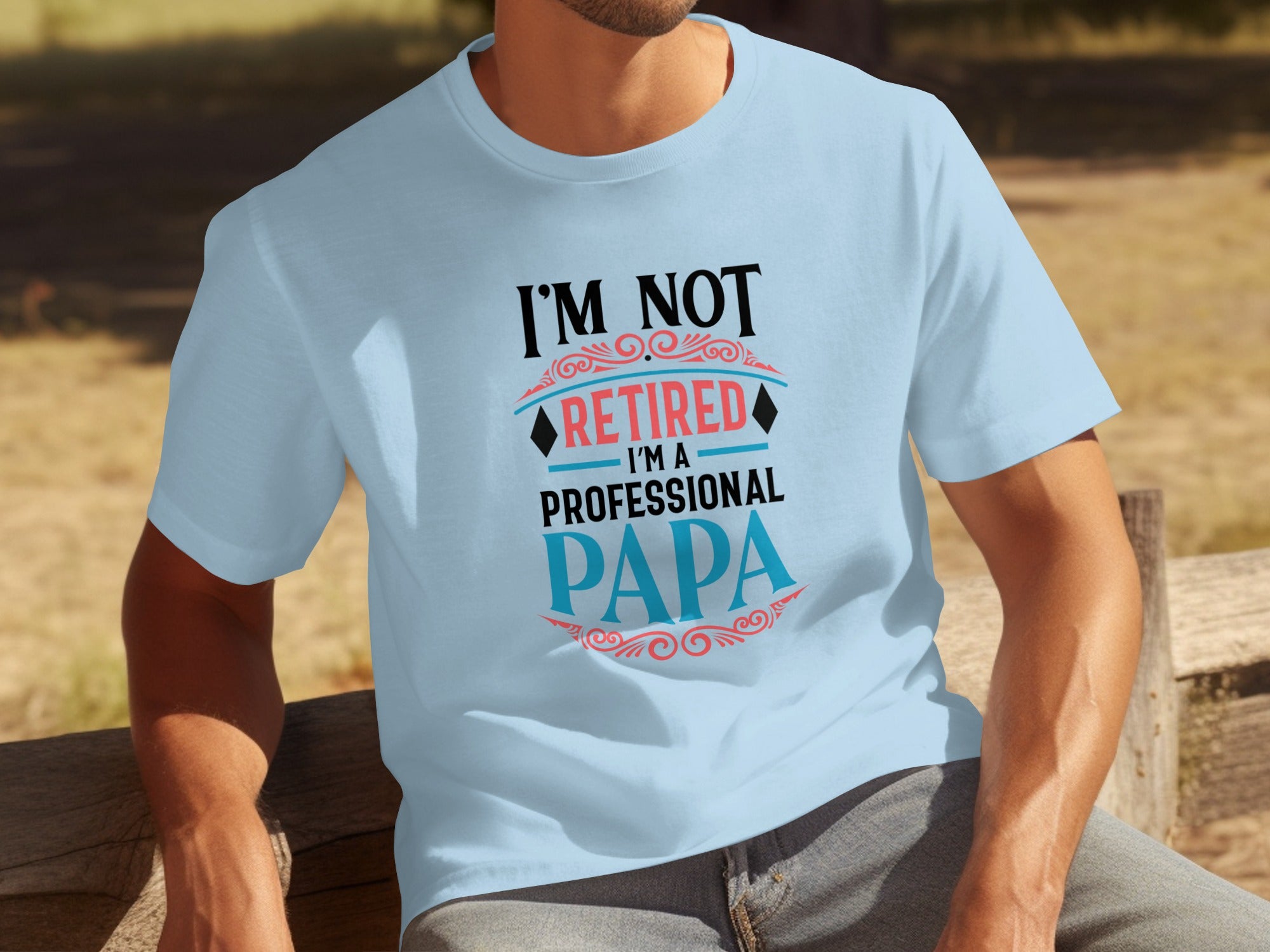 Light blue t-shirt with "I'M NOT RETIRED I'M A PROFESSIONAL PAPA" in black, red, and blue text.