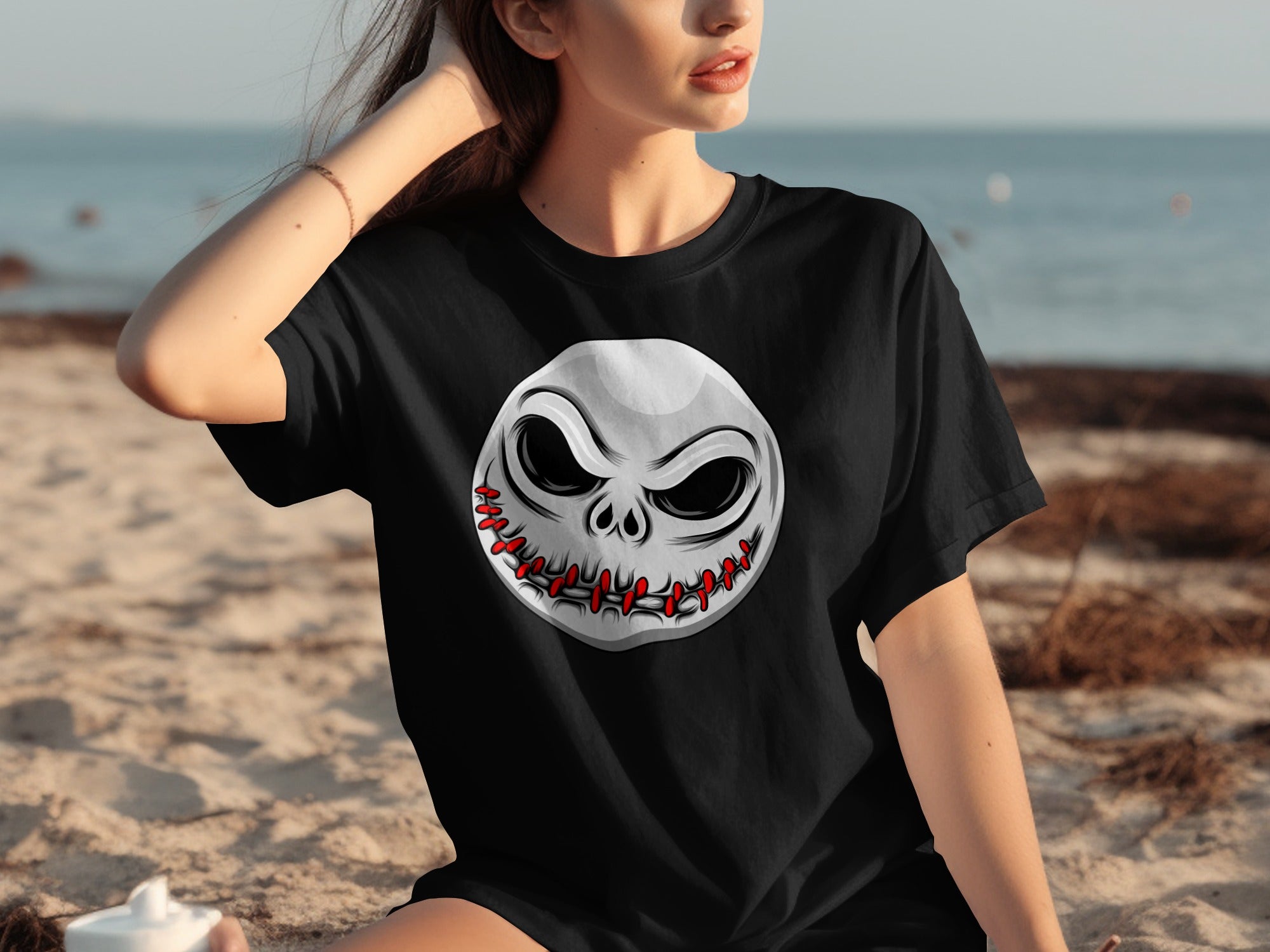 Black t-shirt with a stitched Jack Skellington face graphic on a beach.
