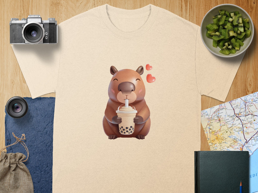 Capybara drinking boba tea with hearts, on a light tan t-shirt.