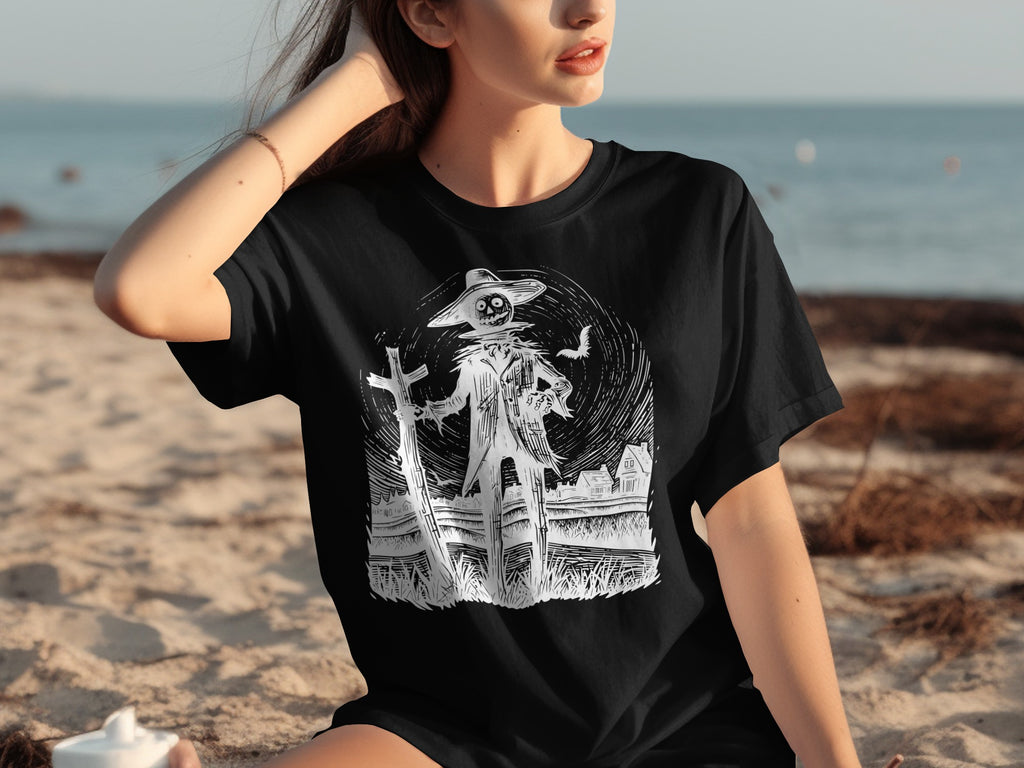Black t-shirt with a monochrome graphic of a scarecrow on a cross with houses and a bat.