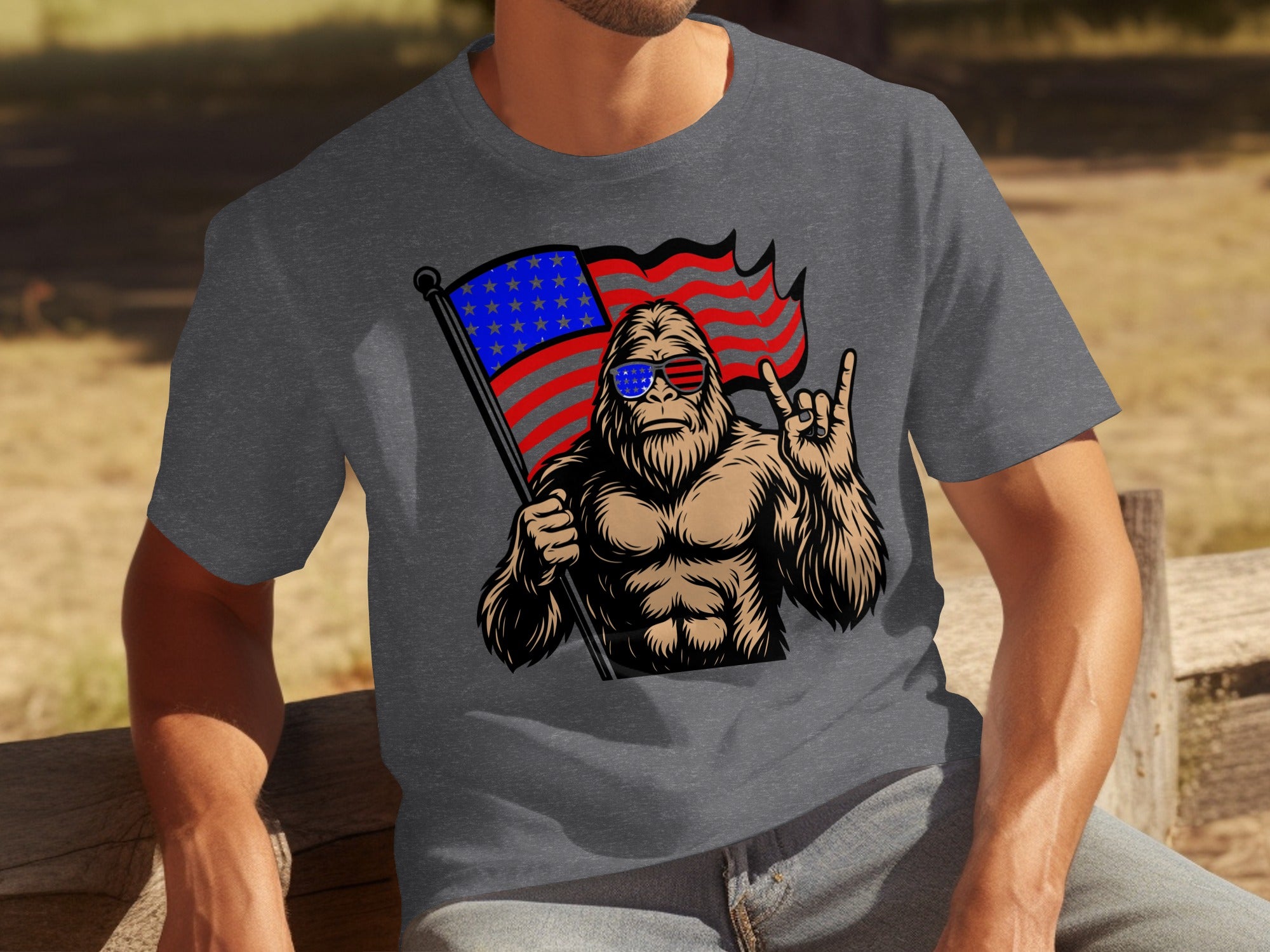Bigfoot wearing American flag sunglasses holds flag and makes rock on hand symbol.