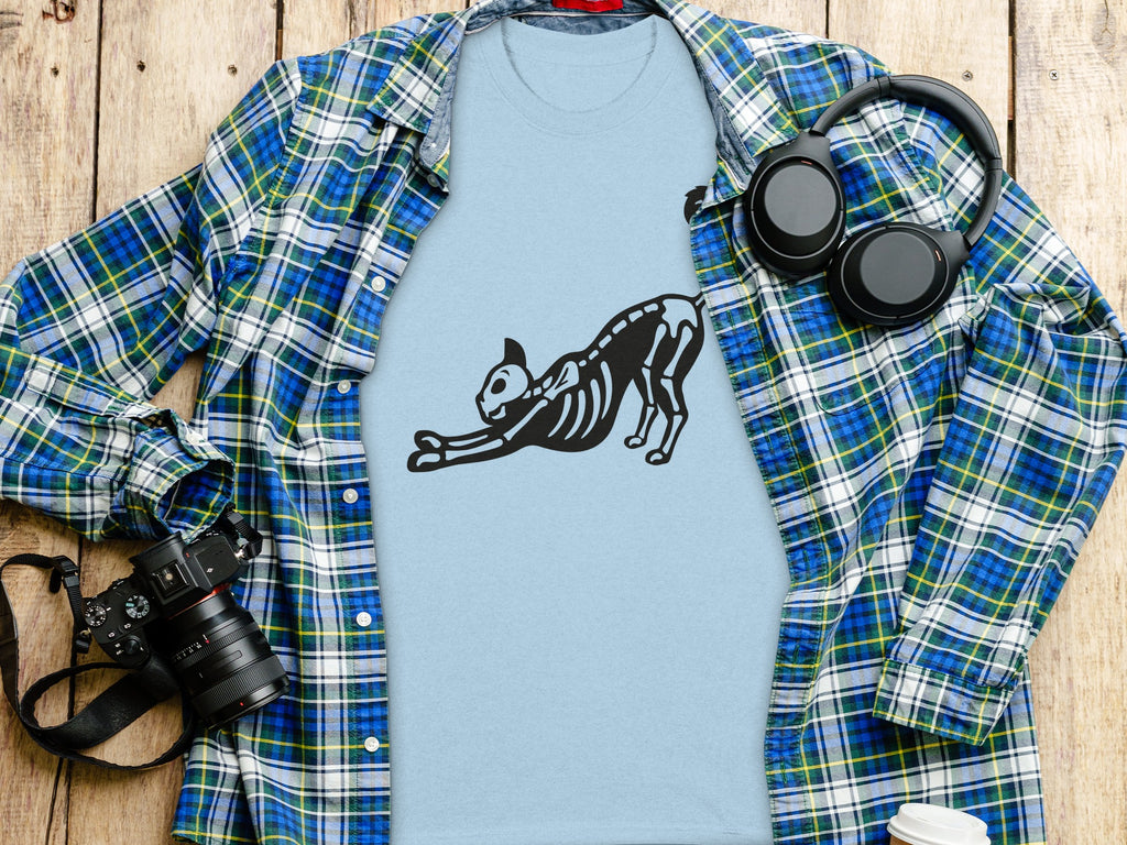 Light blue t-shirt with black cat skeleton design, plaid shirt, headphones, and camera.