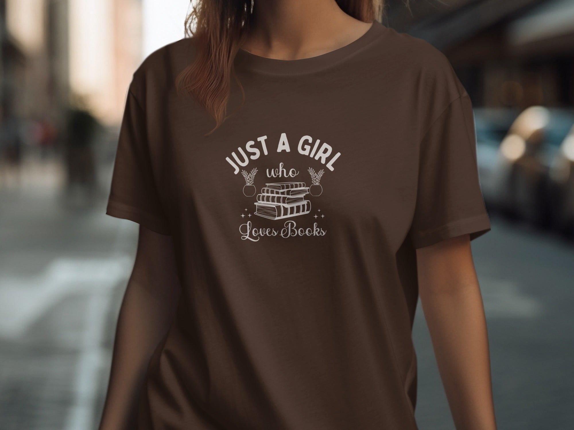 Brown t-shirt with white text reading "Just a girl who loves books" and book illustration.
