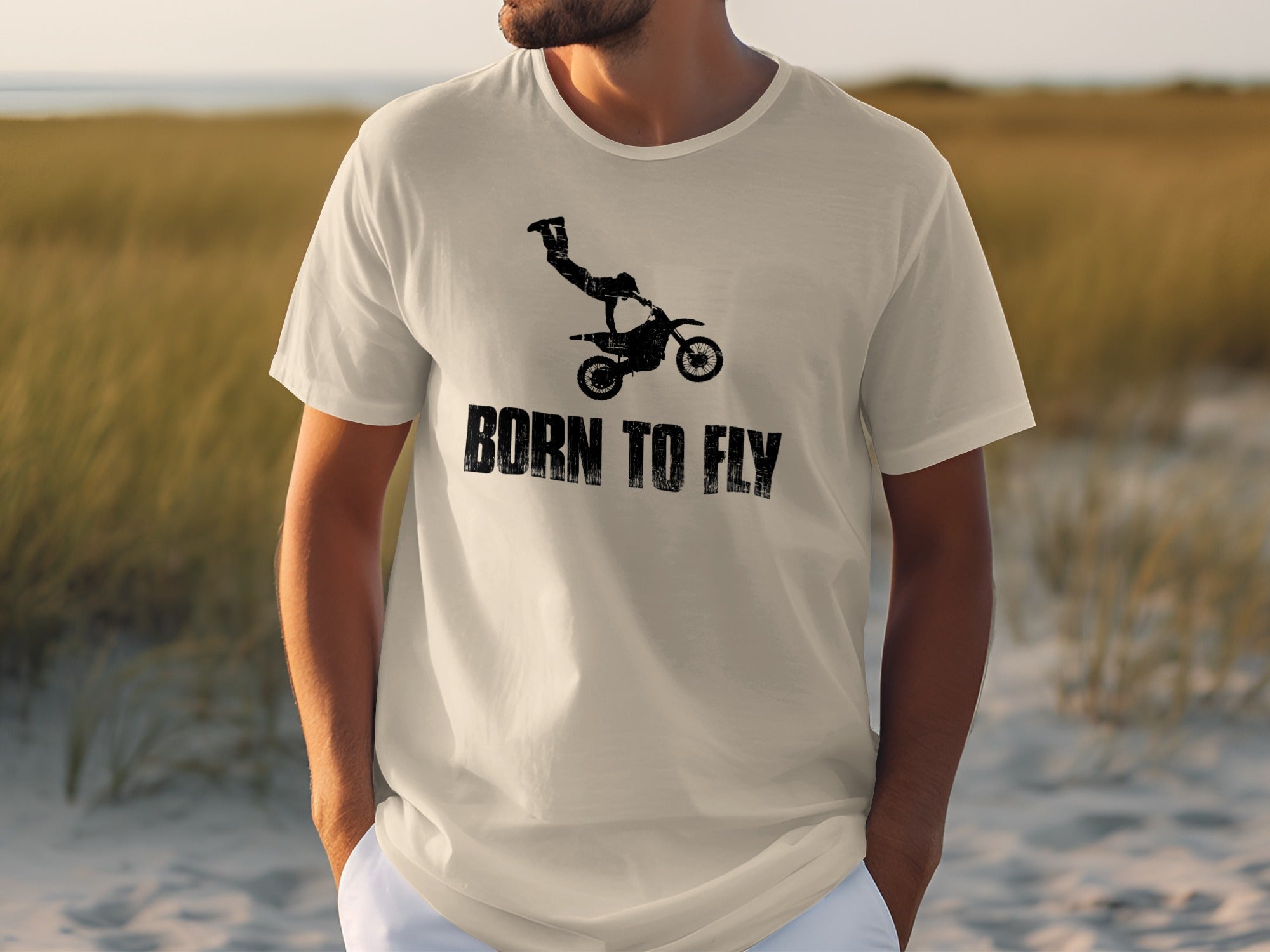 White t-shirt with black distressed graphic of a motocross rider mid-air and text "BORN TO FLY".