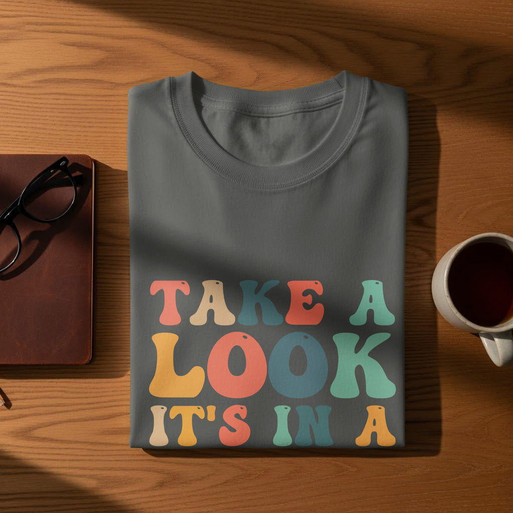 Gray t-shirt with colorful text "TAKE A LOOK IT'S IN A"