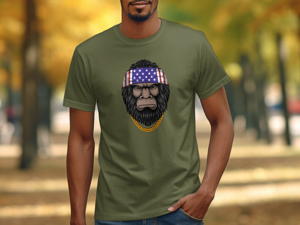 Bigfoot wearing an American flag bandana and gold chain graphic on olive t-shirt.