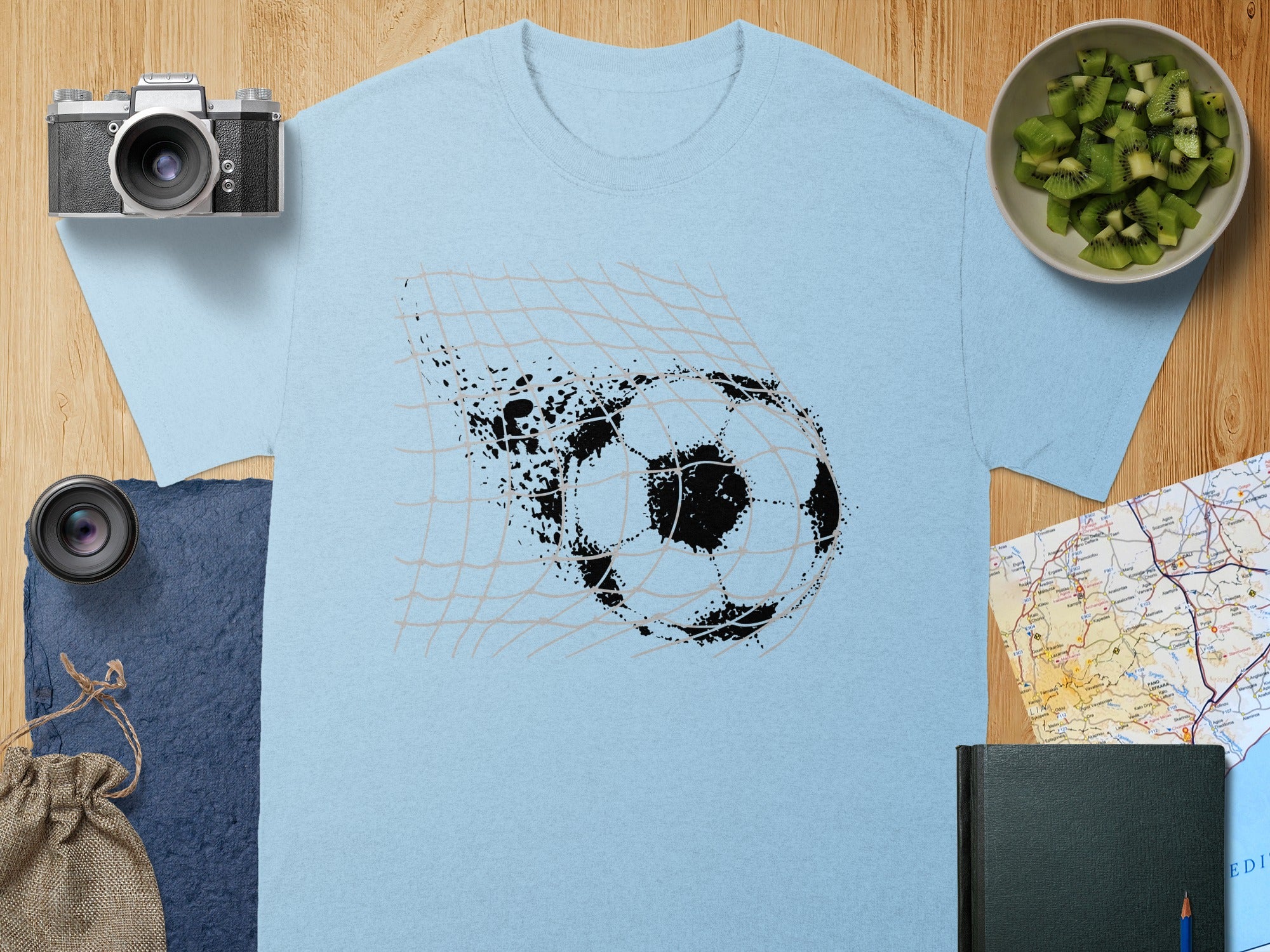Light blue t-shirt with a black football breaking through a net graphic.