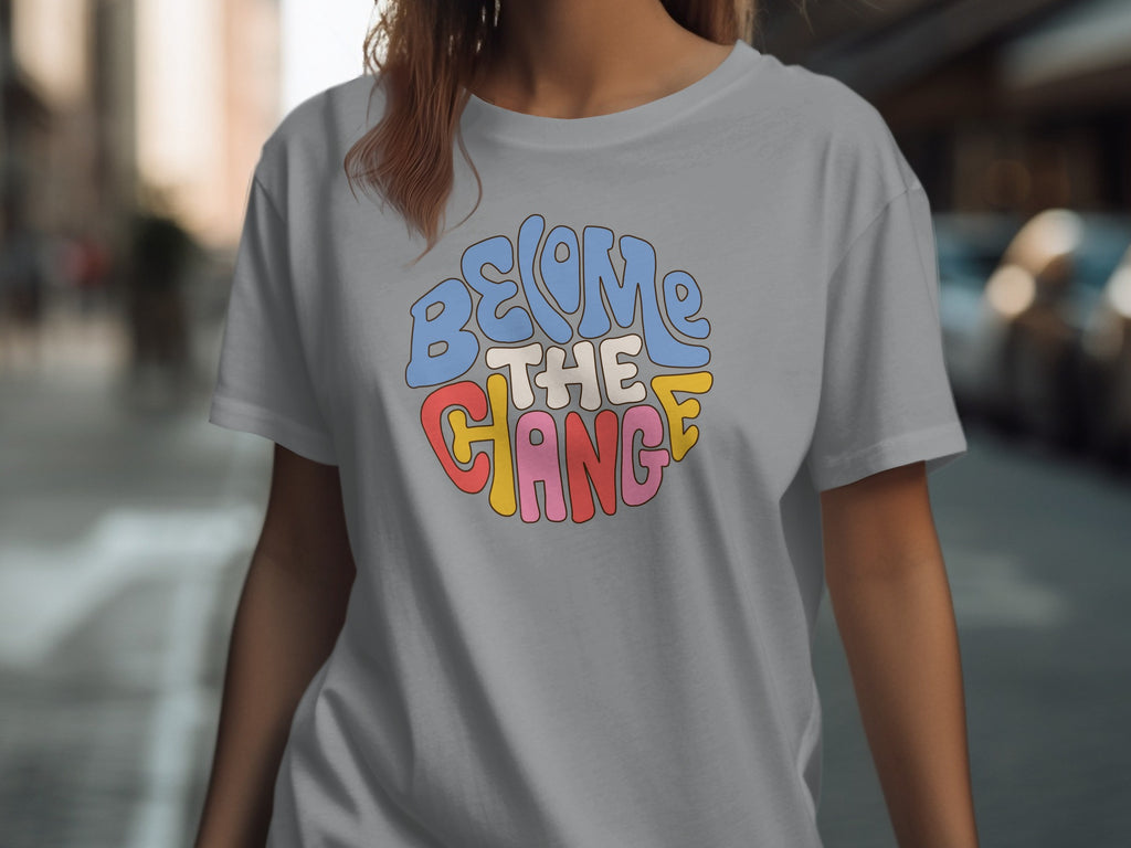 Grey t-shirt with circular text graphic that reads "BECOME THE CHANGE" in colorful retro font.