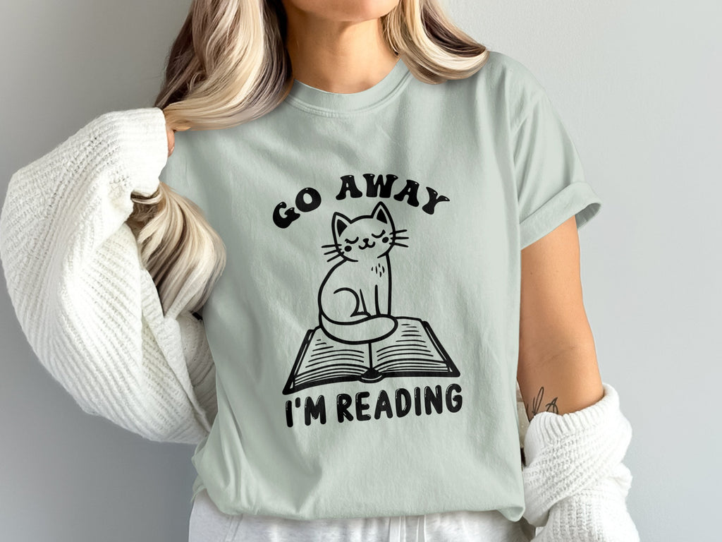 Light mint t-shirt with black graphic "Go Away I'm Reading" and a cat on a book.