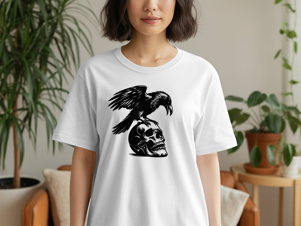 Black raven perched on a skull graphic on a white t-shirt.