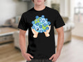 Black t-shirt with a graphic of hands holding a globe surrounded by religious symbols.