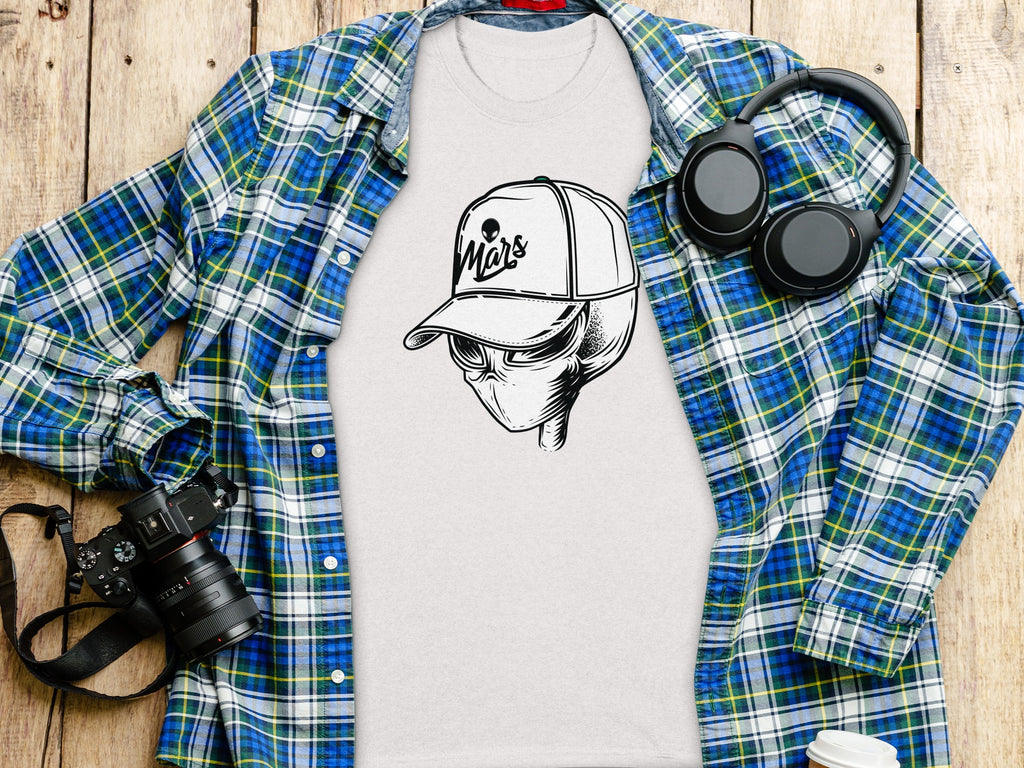 White t-shirt with alien design wearing a cap that says "Mars".