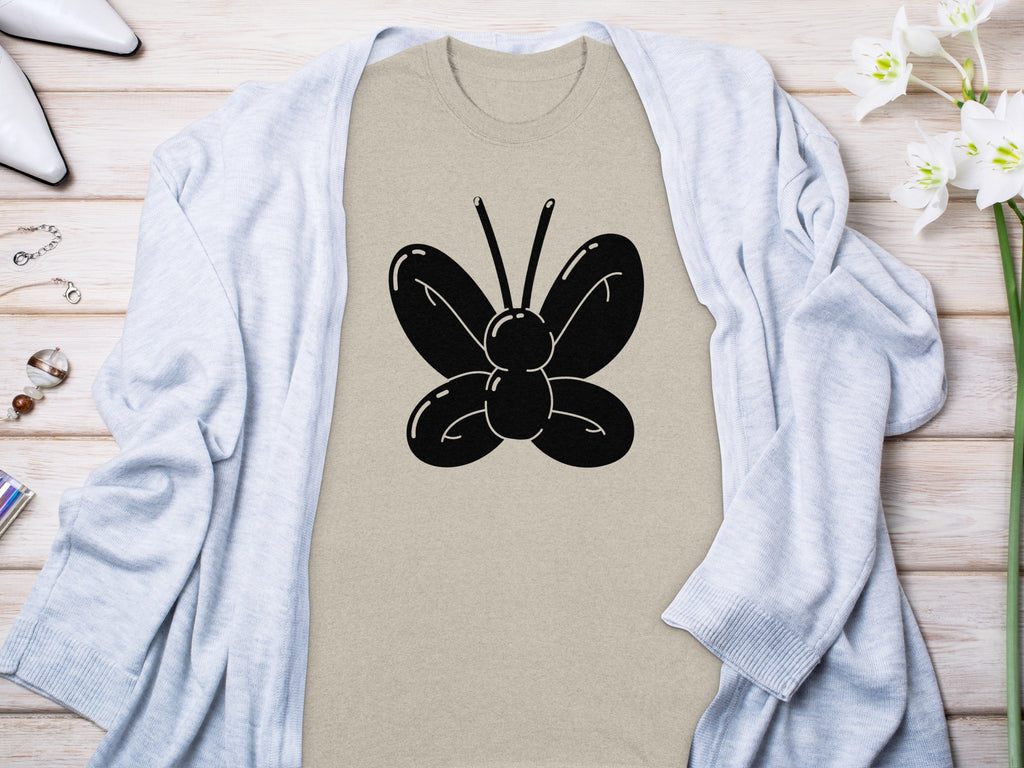 Tan t-shirt with black butterfly graphic, draped with a light blue cardigan.