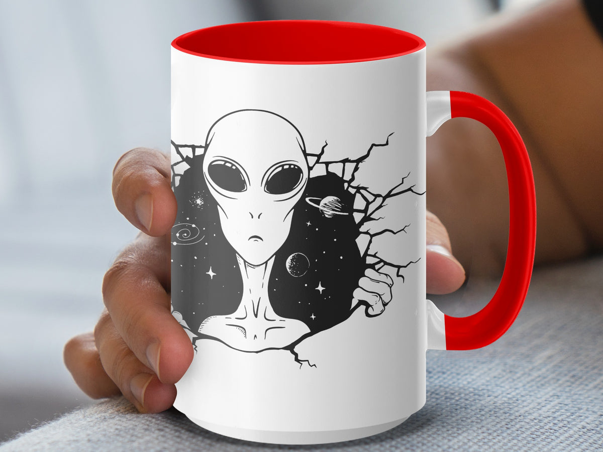 White mug with red handle featuring a black and white alien bursting through a cracked surface.