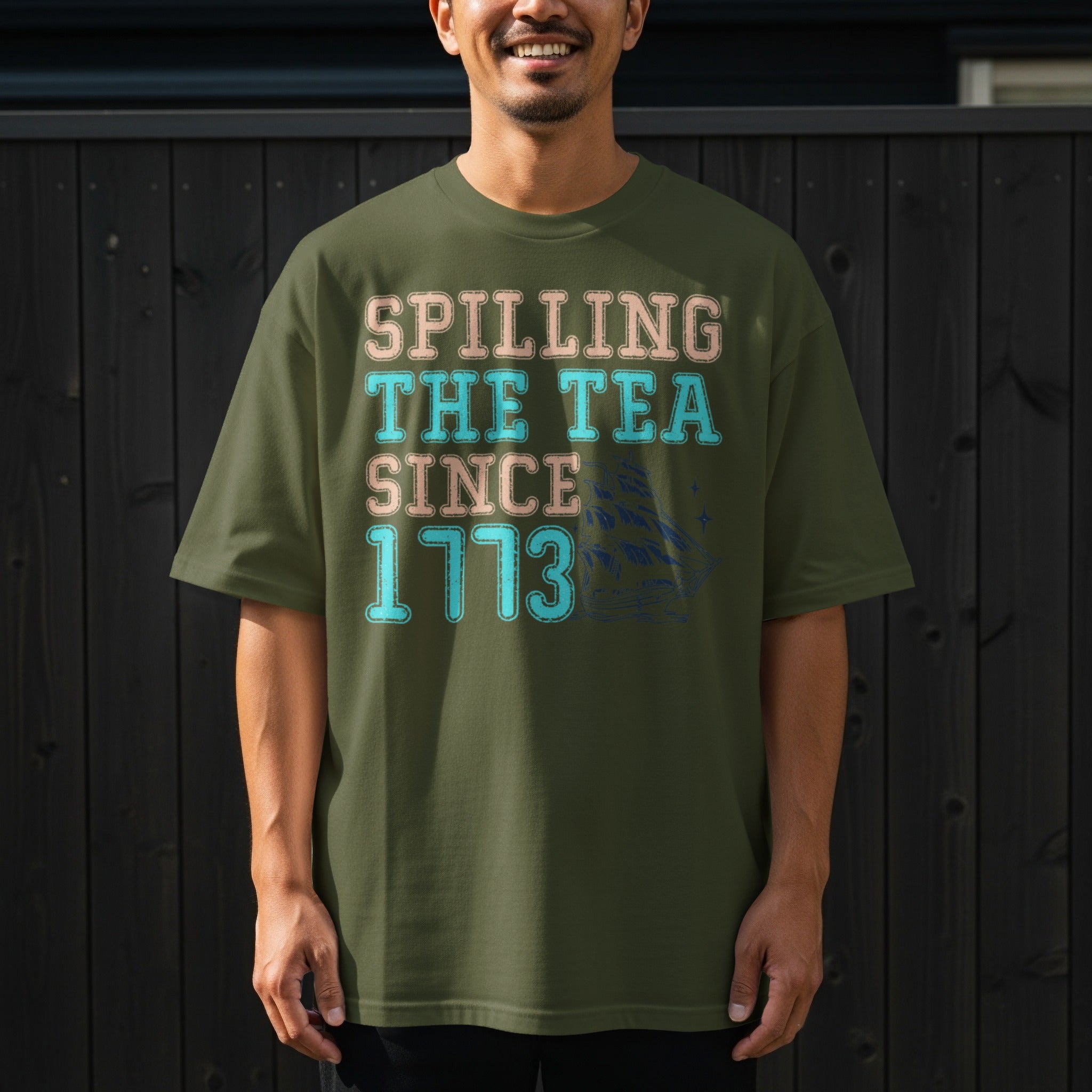 Olive green t-shirt with "Spilling The Tea Since 1773" text and ship graphic.