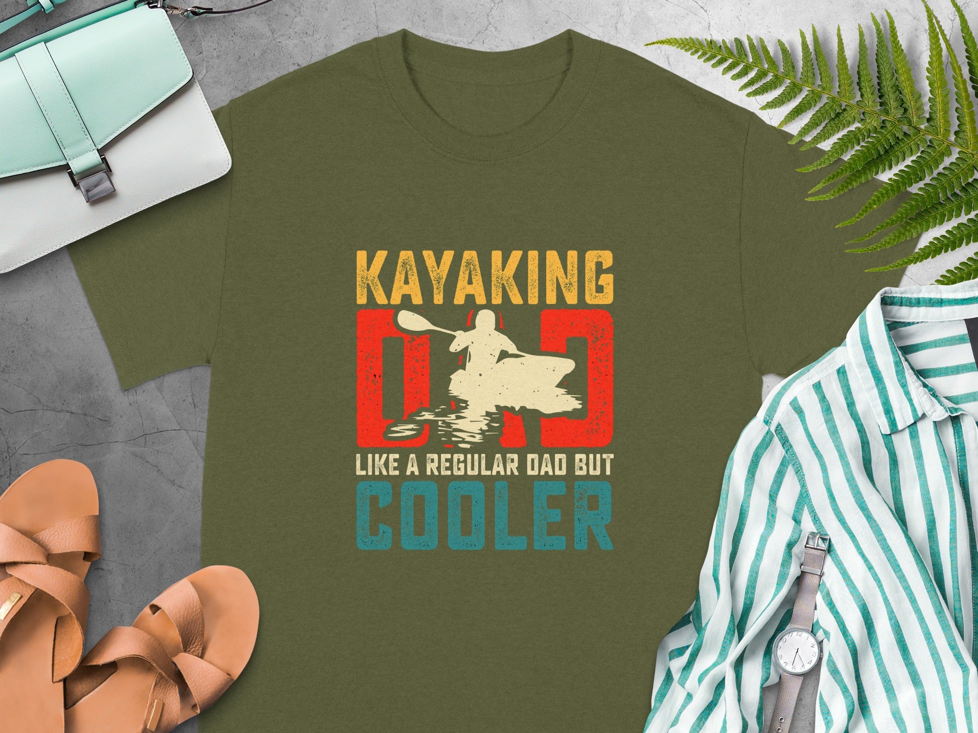 Olive green t-shirt with "Kayaking Dad Like a Regular Dad But Cooler" text and graphic.