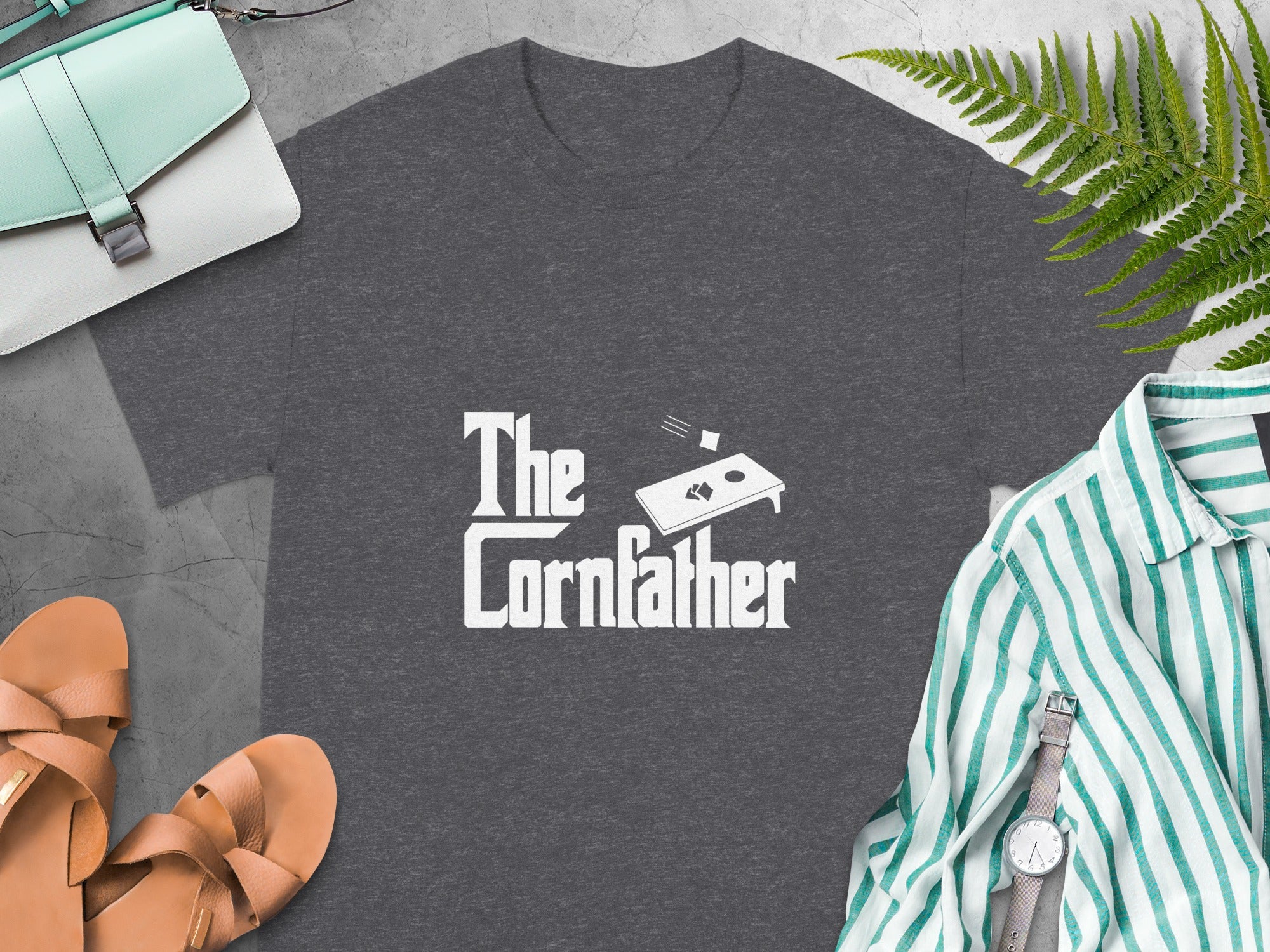 Dark grey t-shirt with "The Cornfather" text and cornhole board graphic.