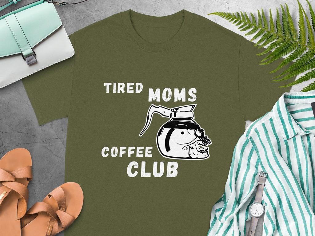 Olive green t-shirt with white text "TIRED MOMS COFFEE CLUB" and skull coffee pot graphic.