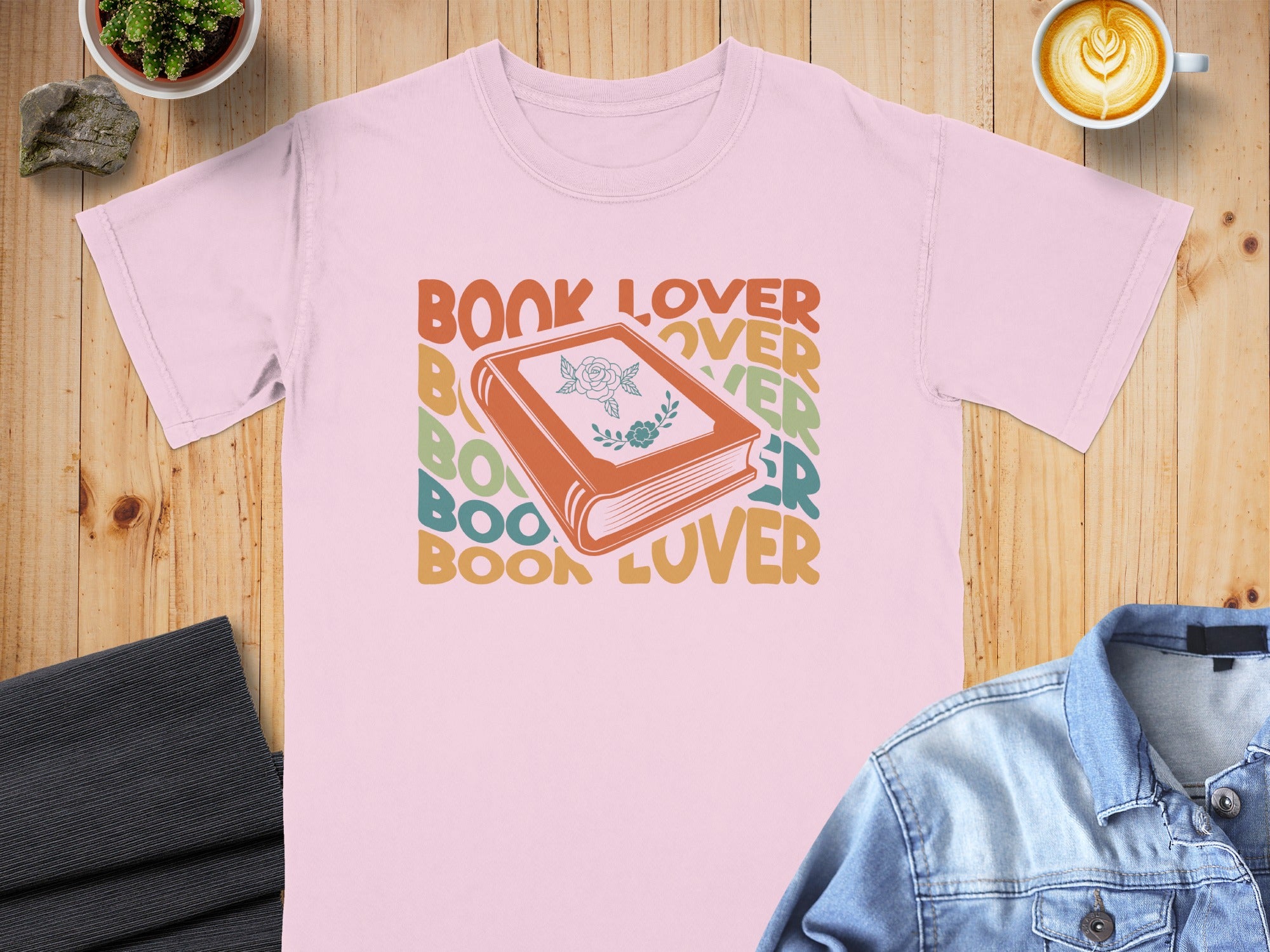 Pink t-shirt with colorful "BOOK LOVER" text and an illustration of a book with a rose.