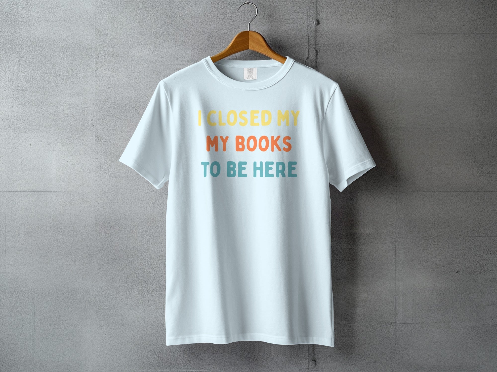 Light blue t-shirt with text "I CLOSED MY MY BOOKS TO BE HERE"