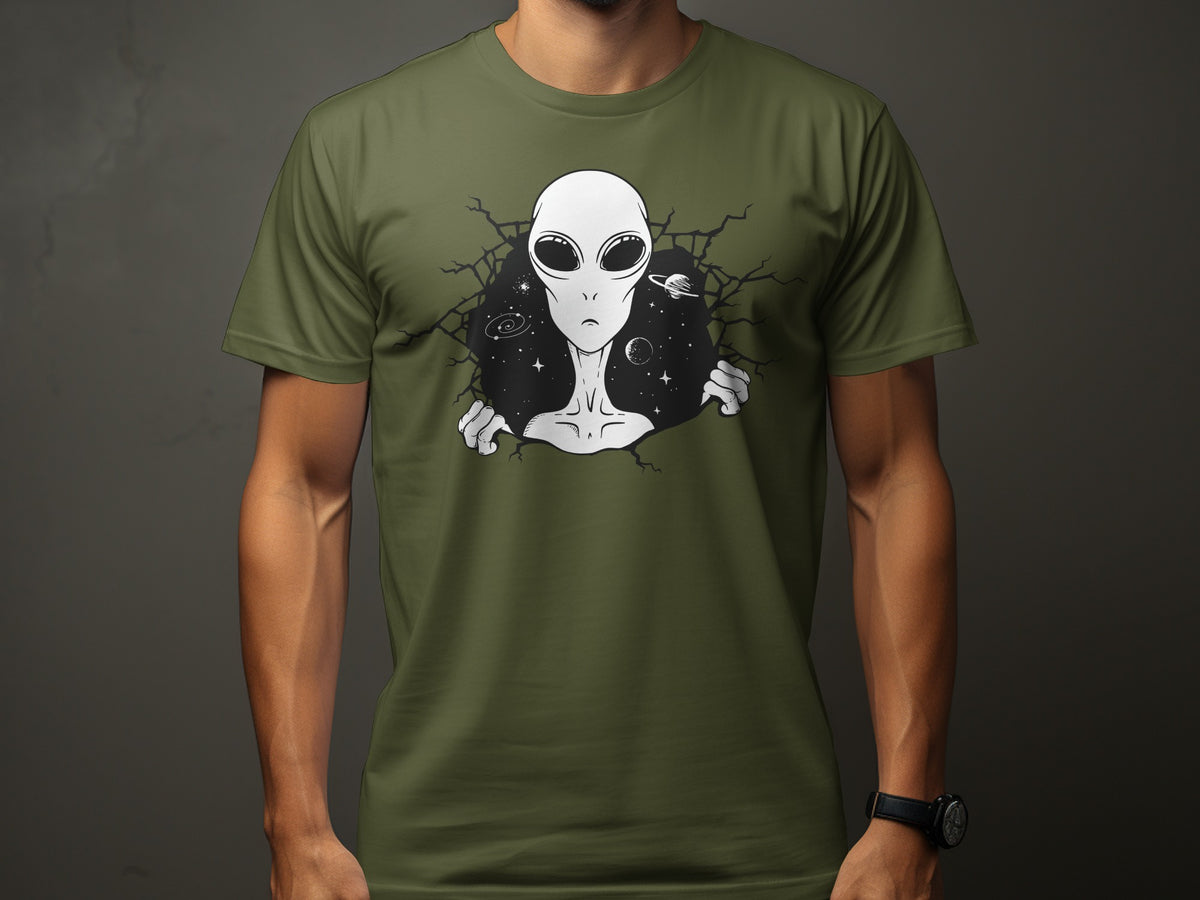 Green t-shirt with a graphic of a grey alien breaking through a cracked circle of space.