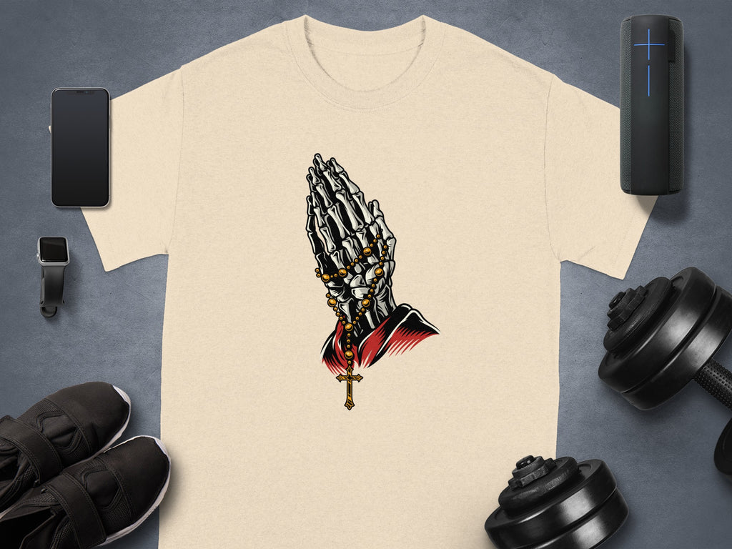 Beige t-shirt with graphic of skeleton hands praying with rosary and cross.