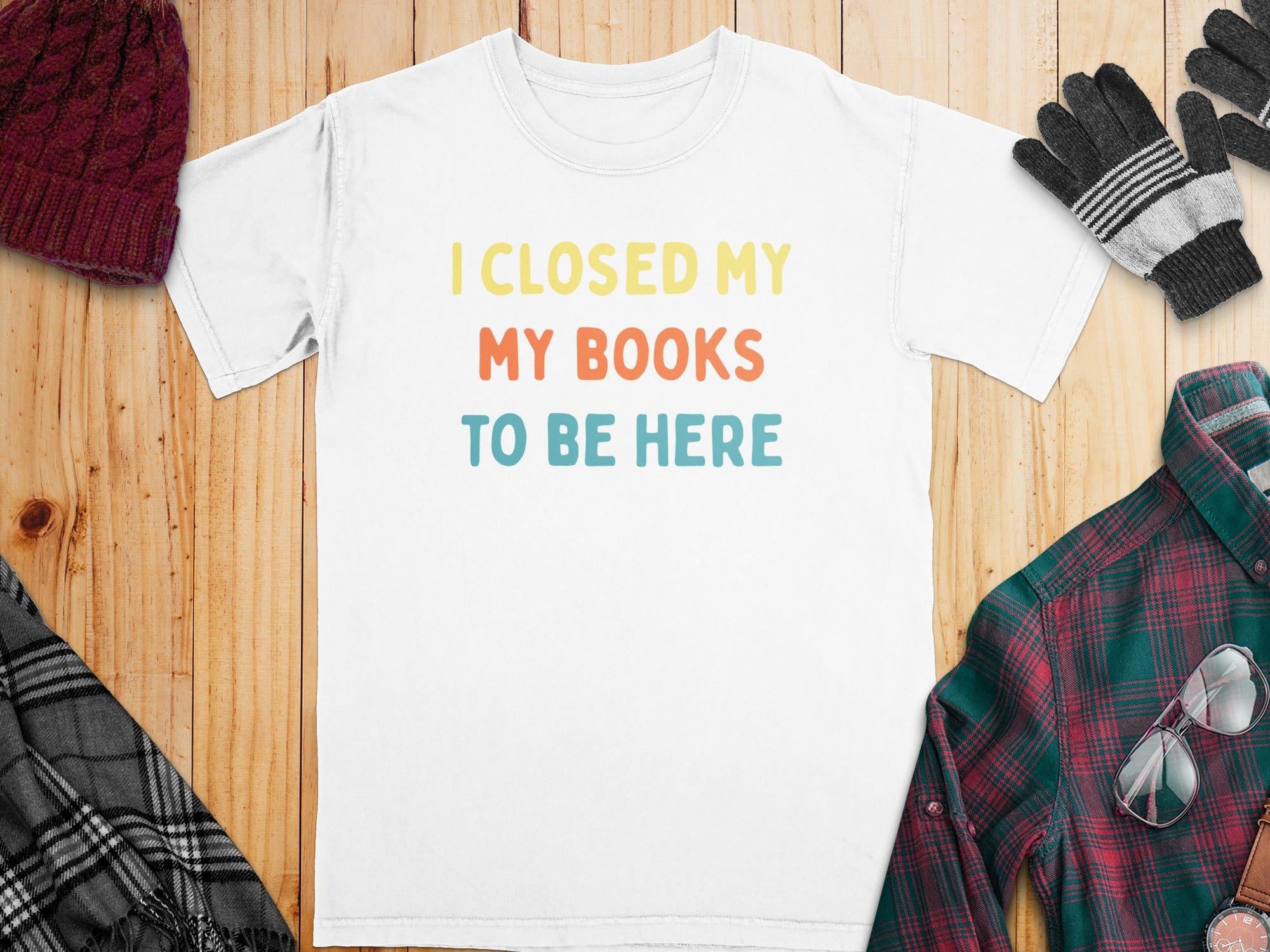 White t-shirt with colorful text: I CLOSED MY MY BOOKS TO BE HERE, surrounded by autumn accessories.