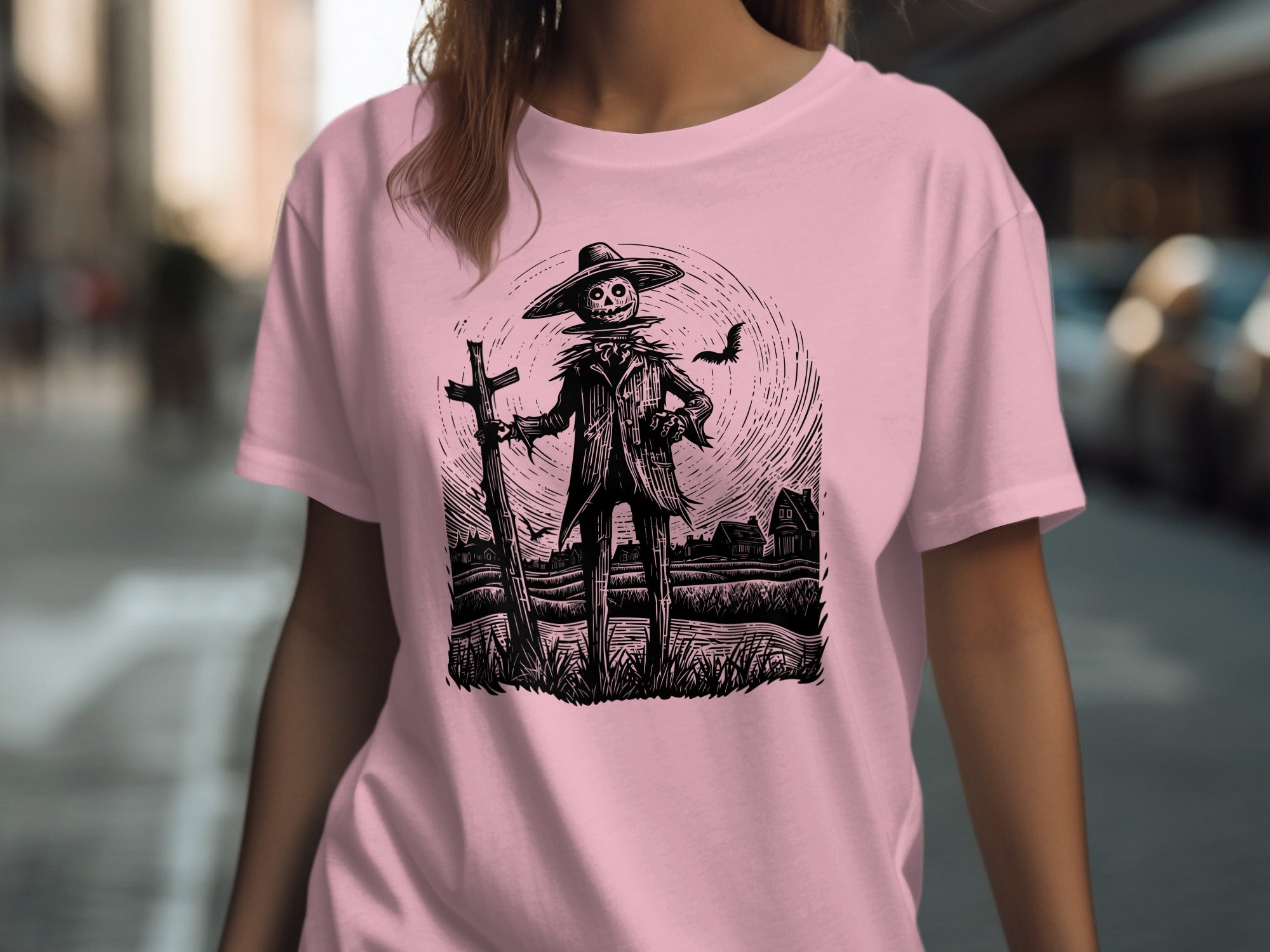Scarecrow in a hat with a cross and bat illustration on a pink t-shirt.