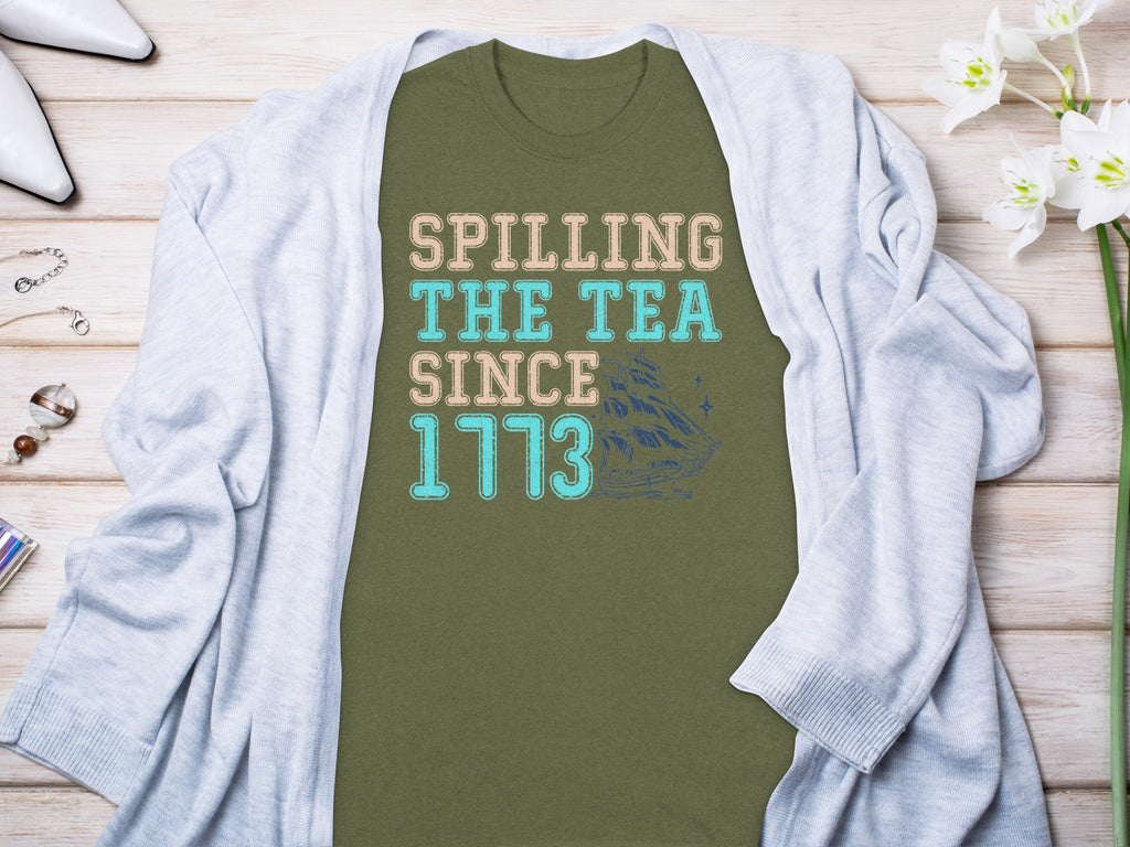 Green t-shirt with text "SPILLING THE TEA SINCE 1773" and a sailboat graphic.