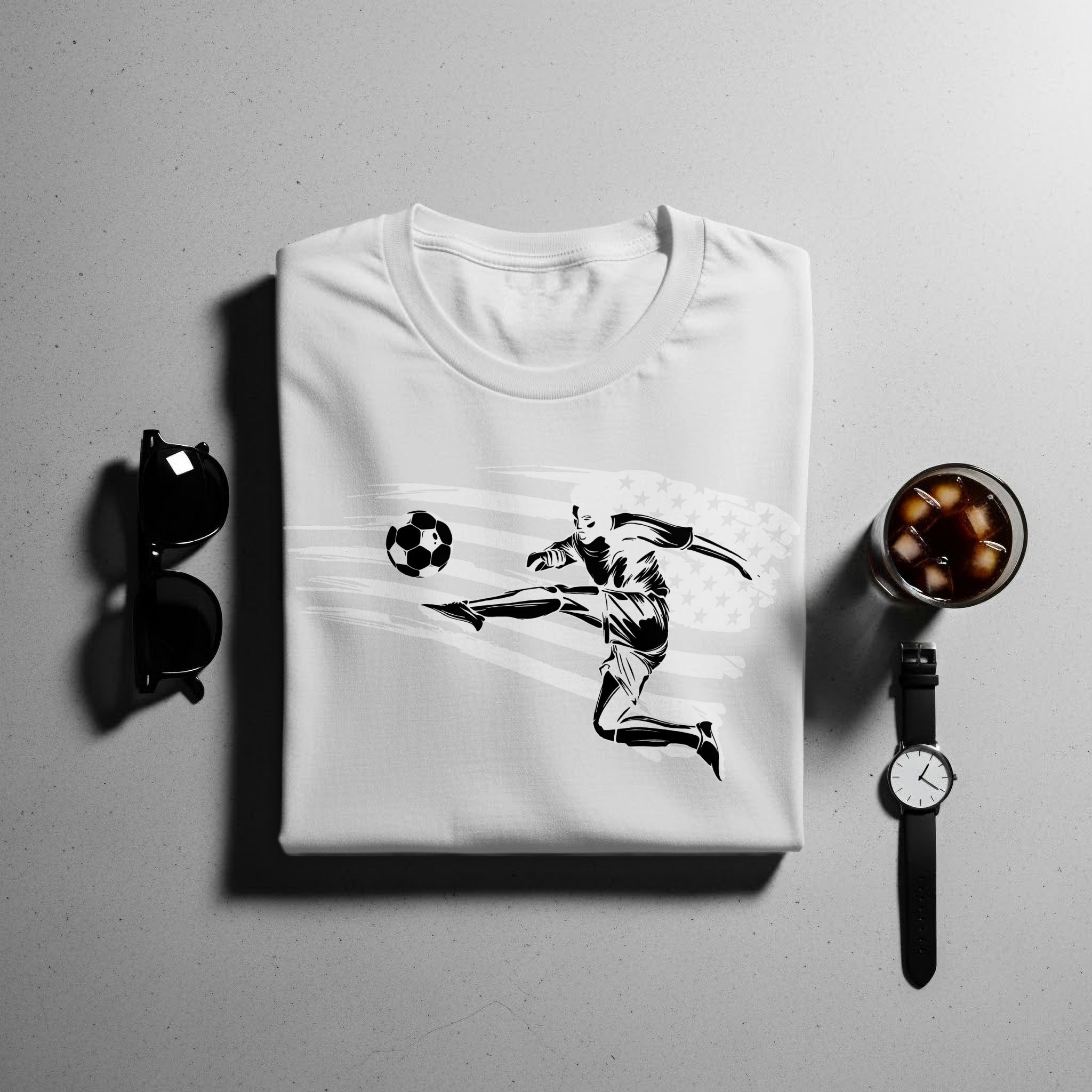 White t-shirt with black graphic of a soccer player kicking a ball and US flag.