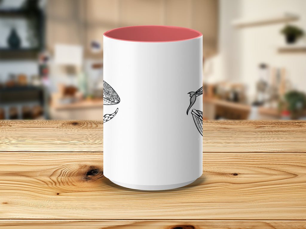 White mug with intricate black line art of two fish against a blurred kitchen background.