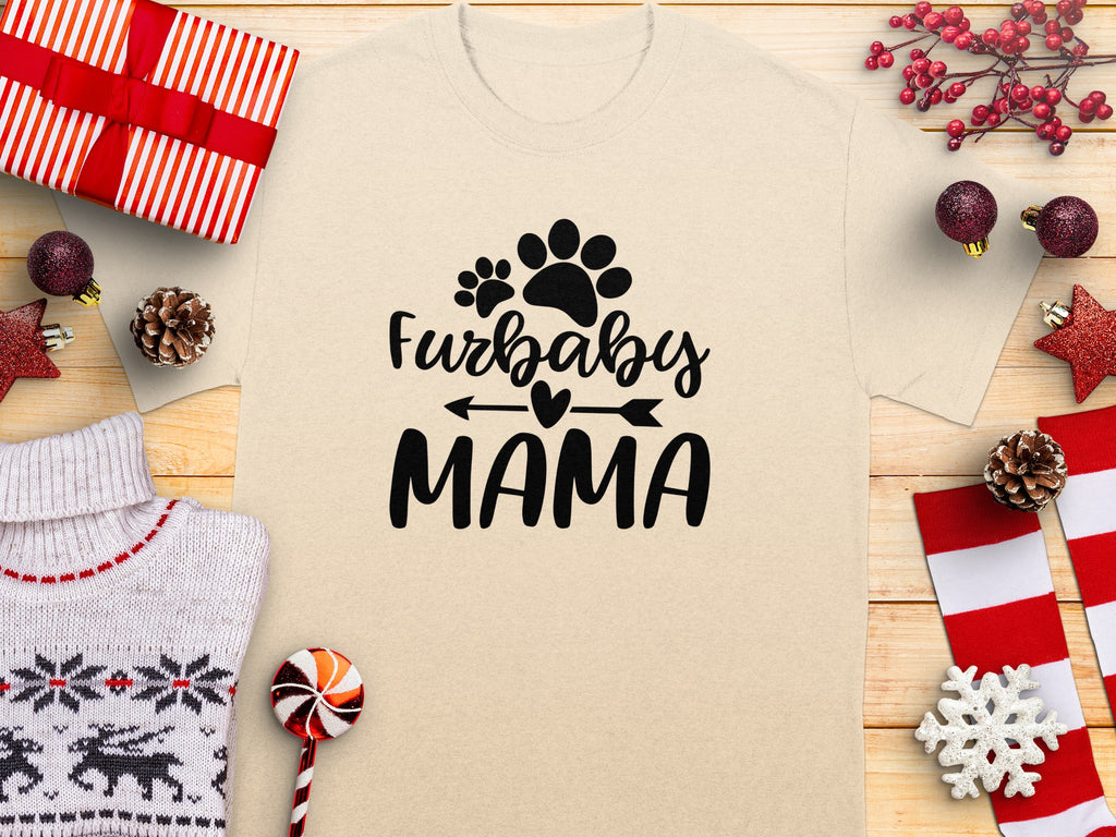 Furbaby Mama text with paw prints on a tan t-shirt, surrounded by holiday decor.
