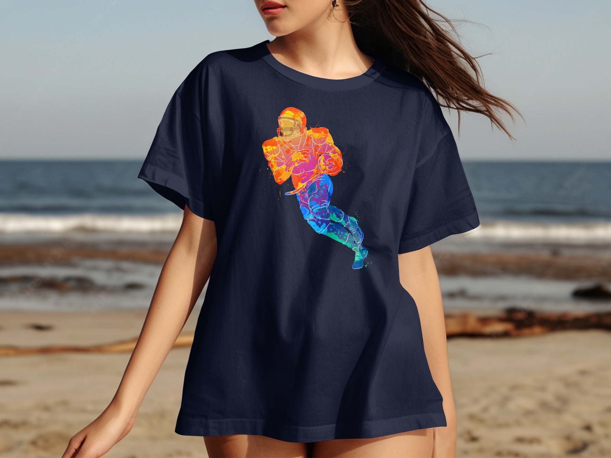 Navy t-shirt with colorful watercolor football player graphic on beach background.