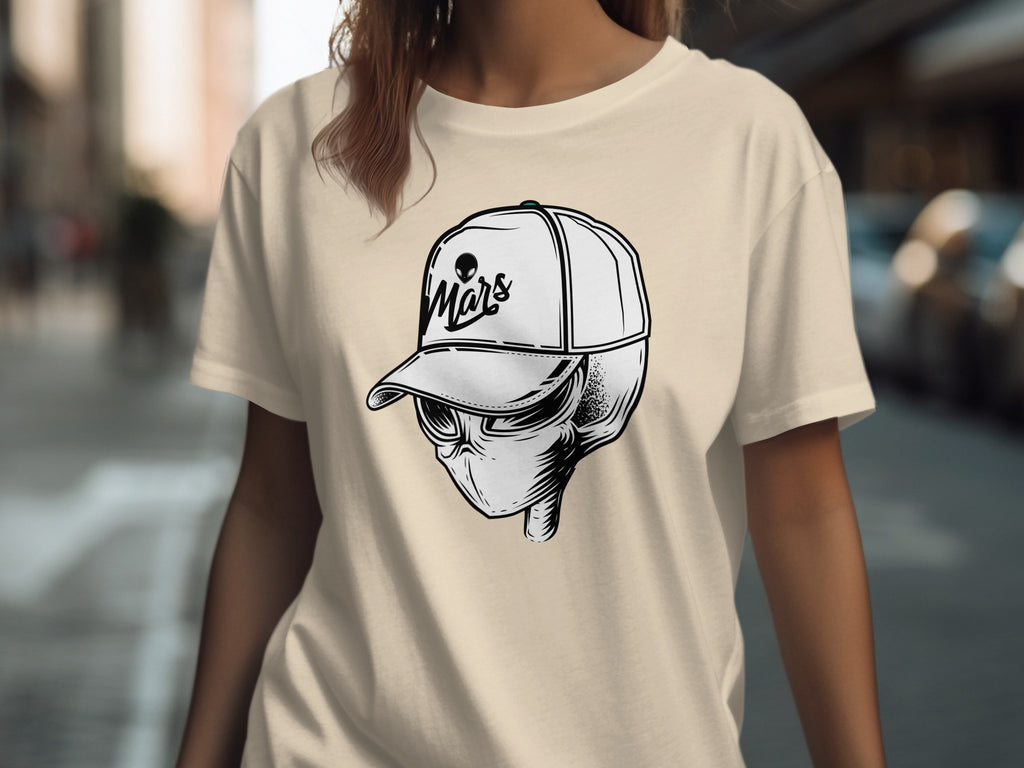 Black and white alien skull wearing a baseball cap with "Mars" text on a cream t-shirt.